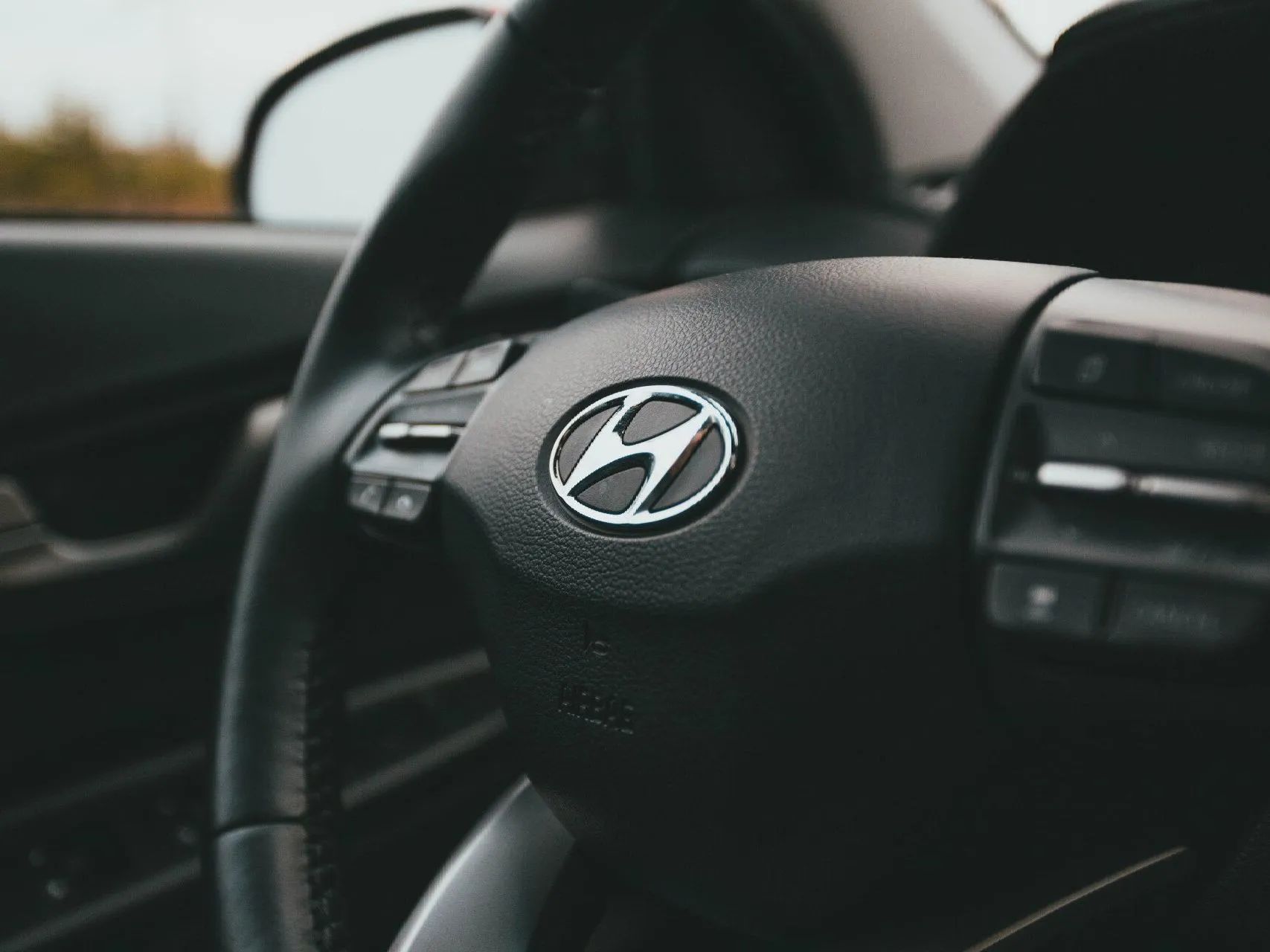 Steering wheel of a Hyundai car with the company logo.