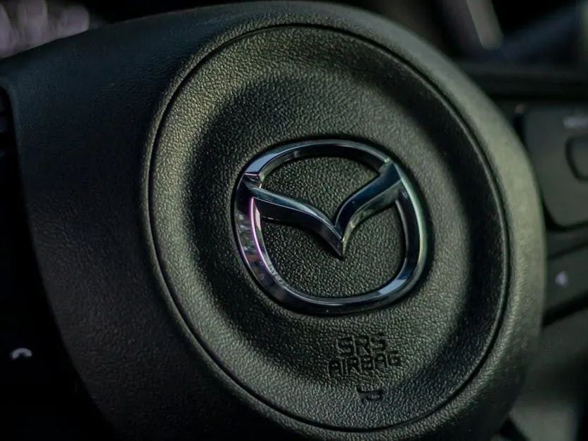 Close-up of a black Mazda steering wheel with the Mazda logo at the center.