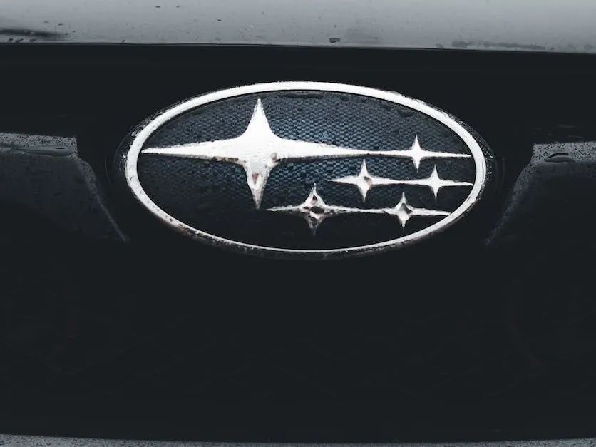 Subaru car emblem, silver stars on a blue oval, set on a black car grill.