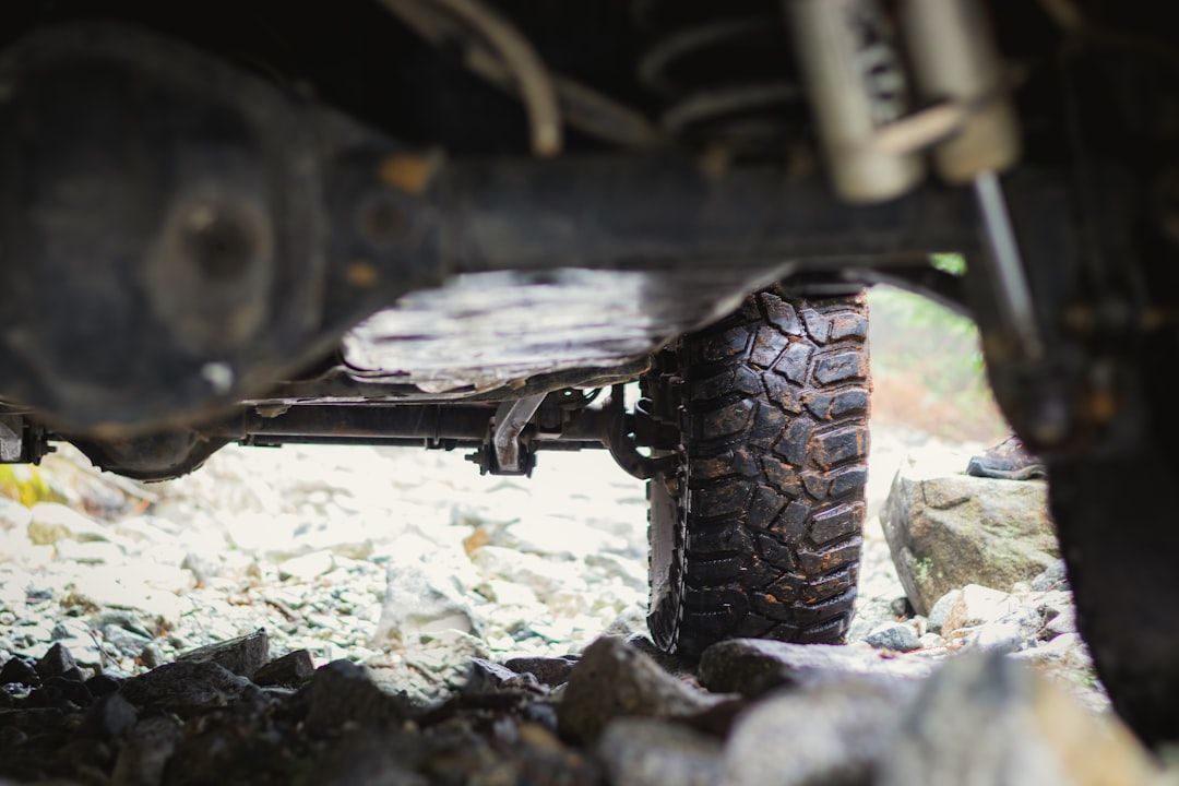 Underside of a 4x4 vehicle's tire, driving over rocky terrain; black rubber, wet.