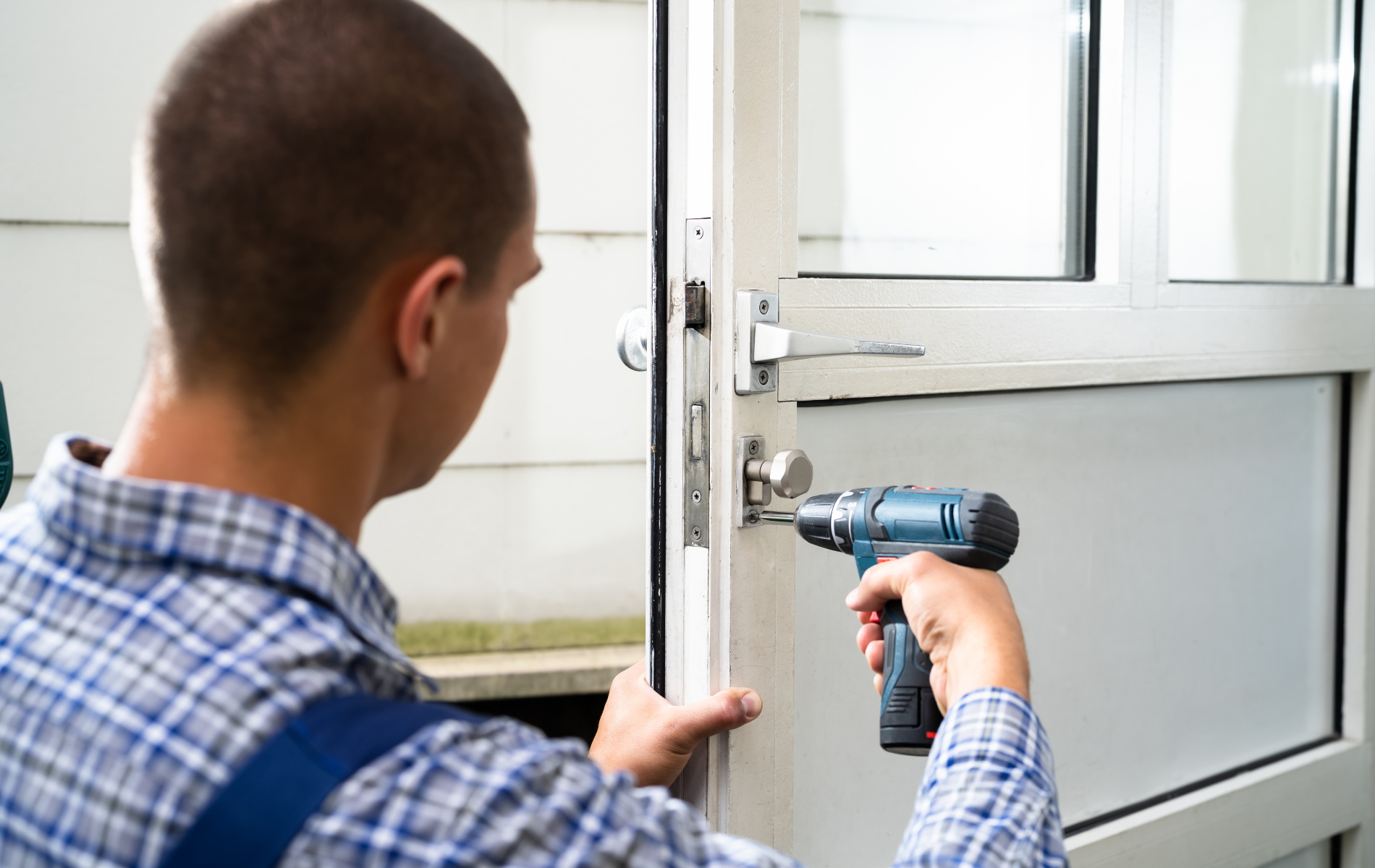 Man using a drill on a door, working on the lock.