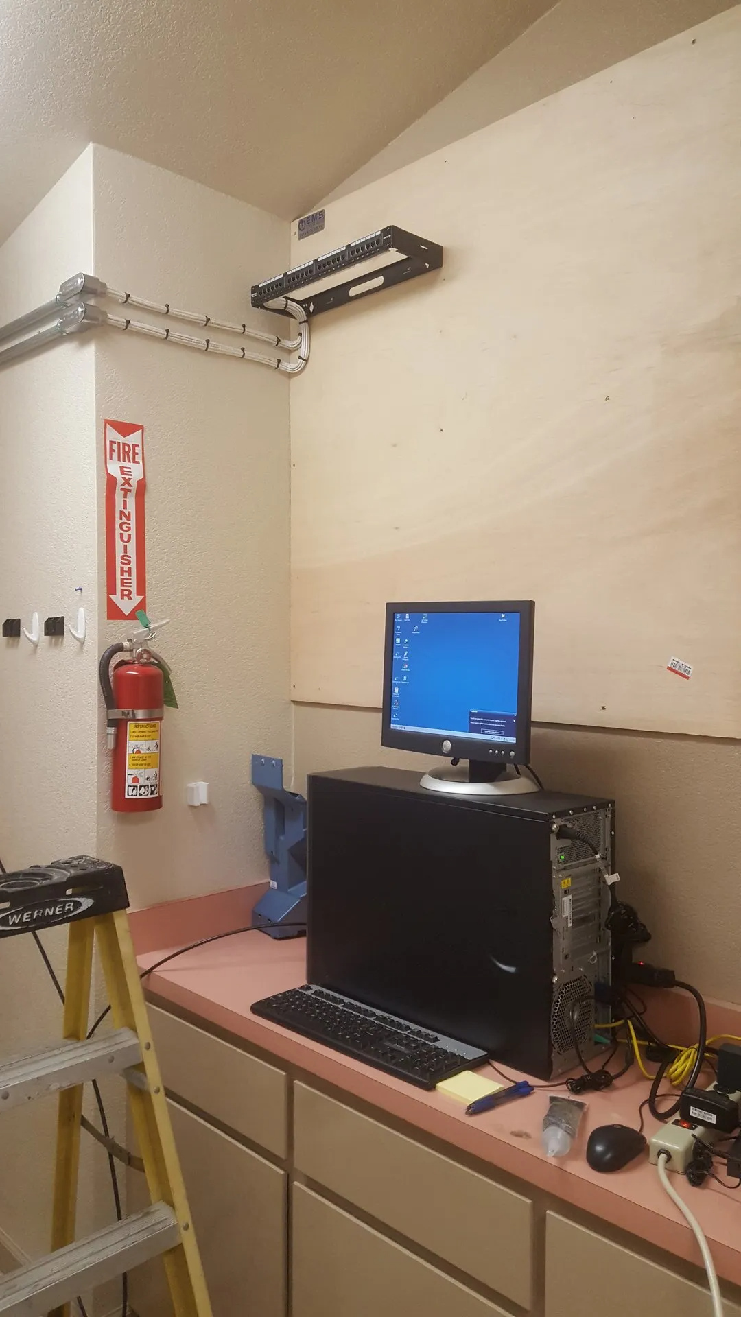 Ein Computer steht neben einem Feuerlöscher auf einer Theke.