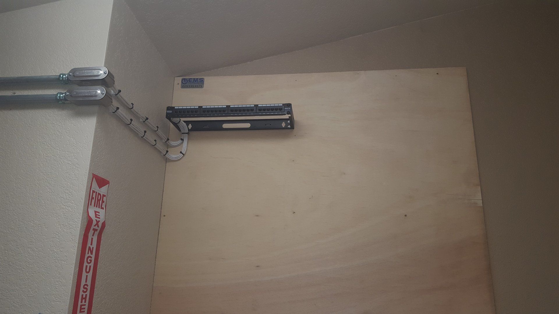 Un pezzo di legno è appoggiato su un muro accanto a un cartello rosso.