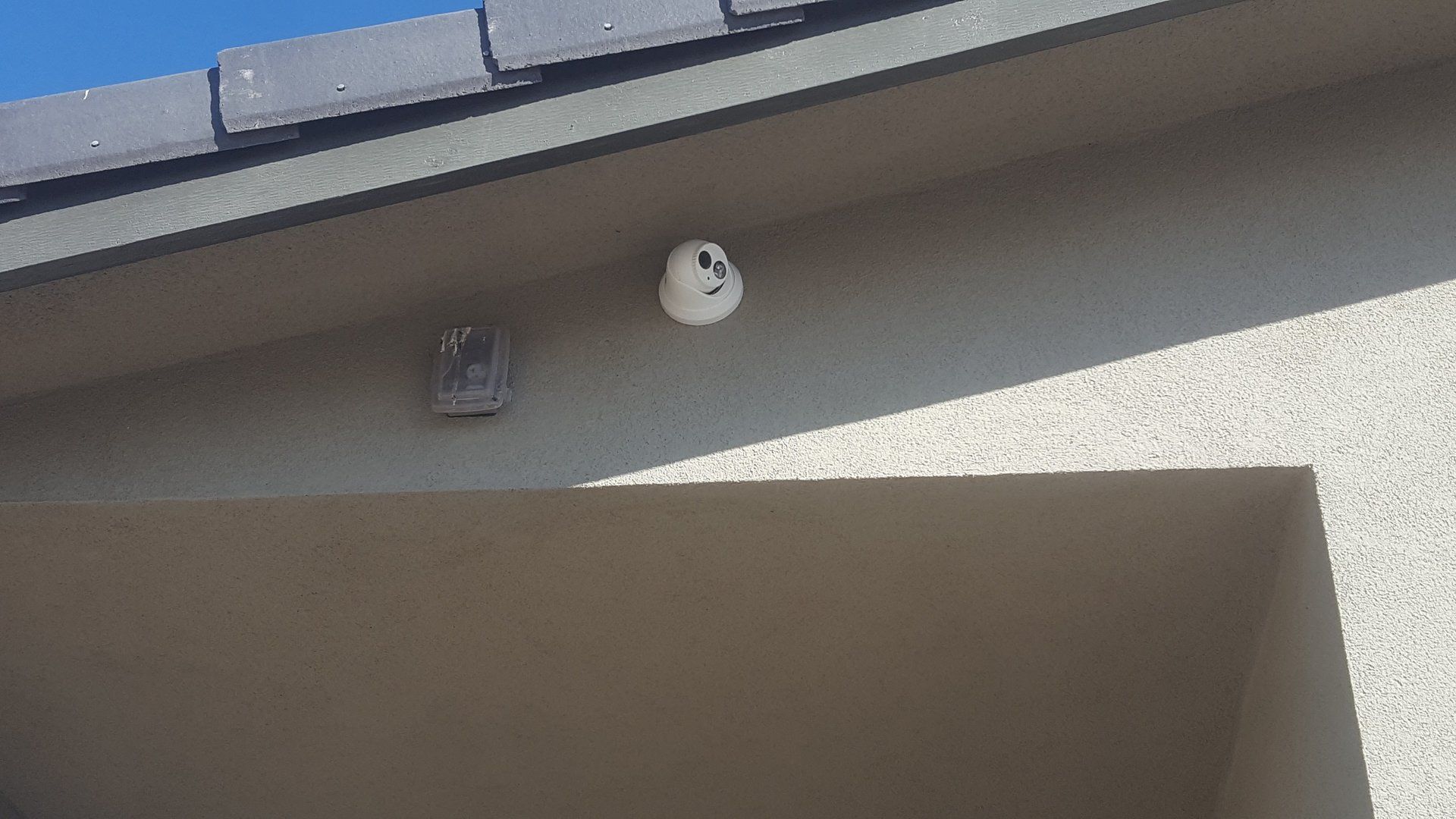 A white object is hanging from the roof of a building.