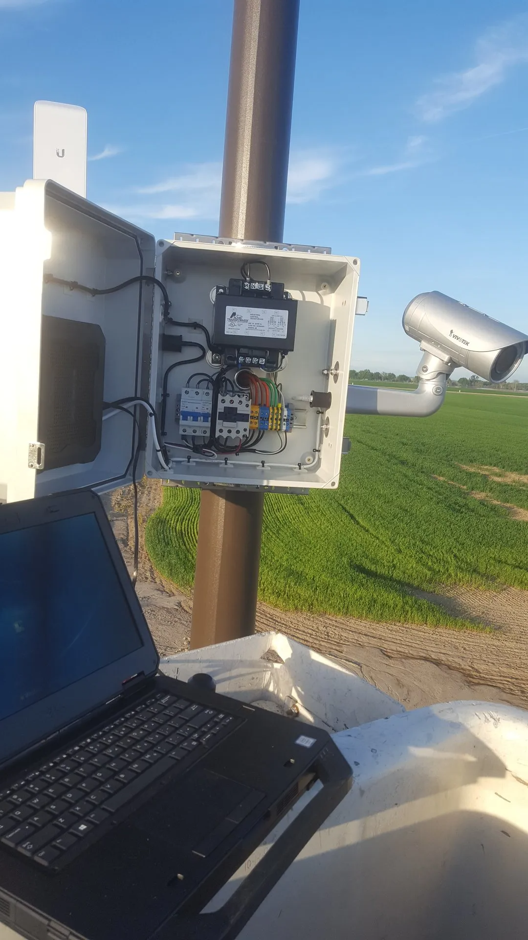 A laptop is sitting on top of a table next to a box and a camera.