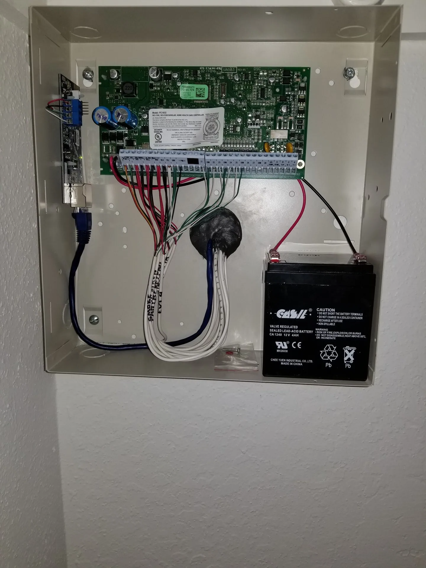 The inside of a security system with a battery and wires.
