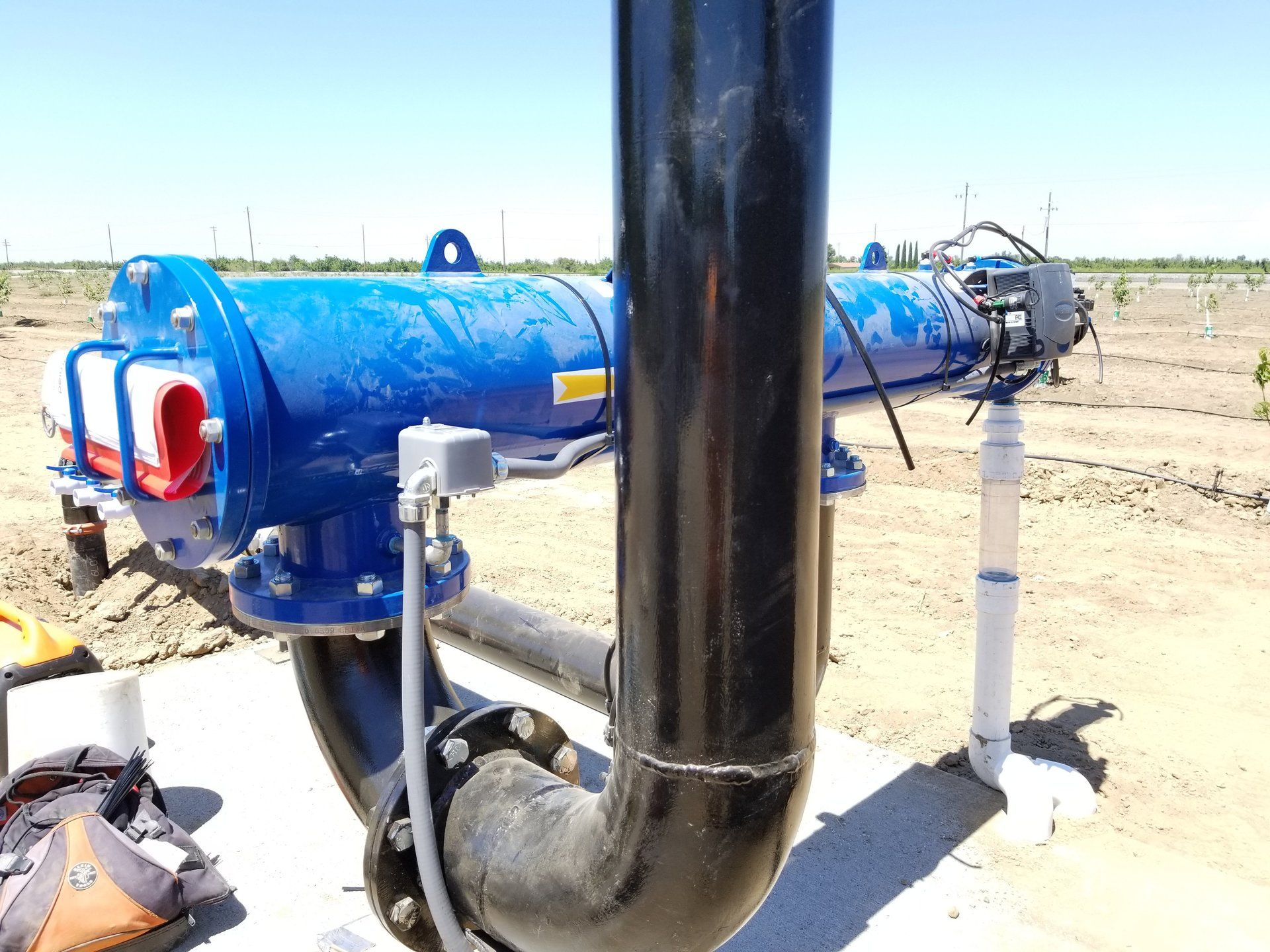 A blue pipe is connected to a black pipe in a field.