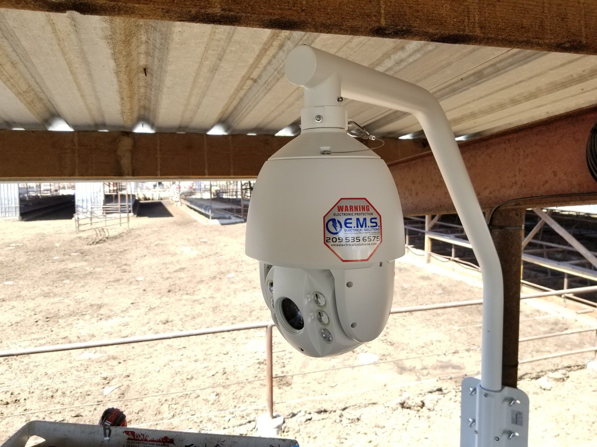 A security camera is hanging from a pole under a roof.