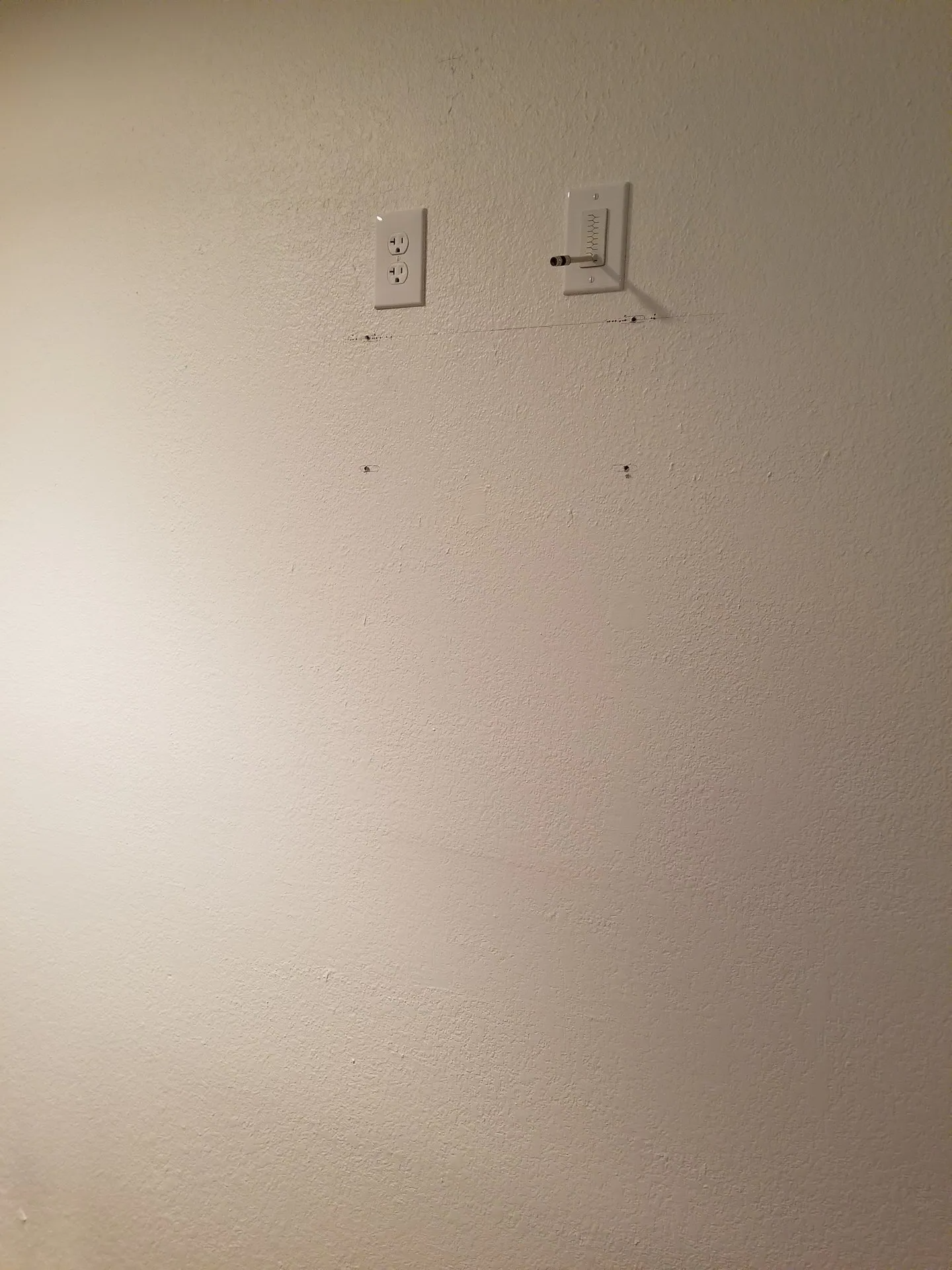 A white wall with two electrical outlets on it.