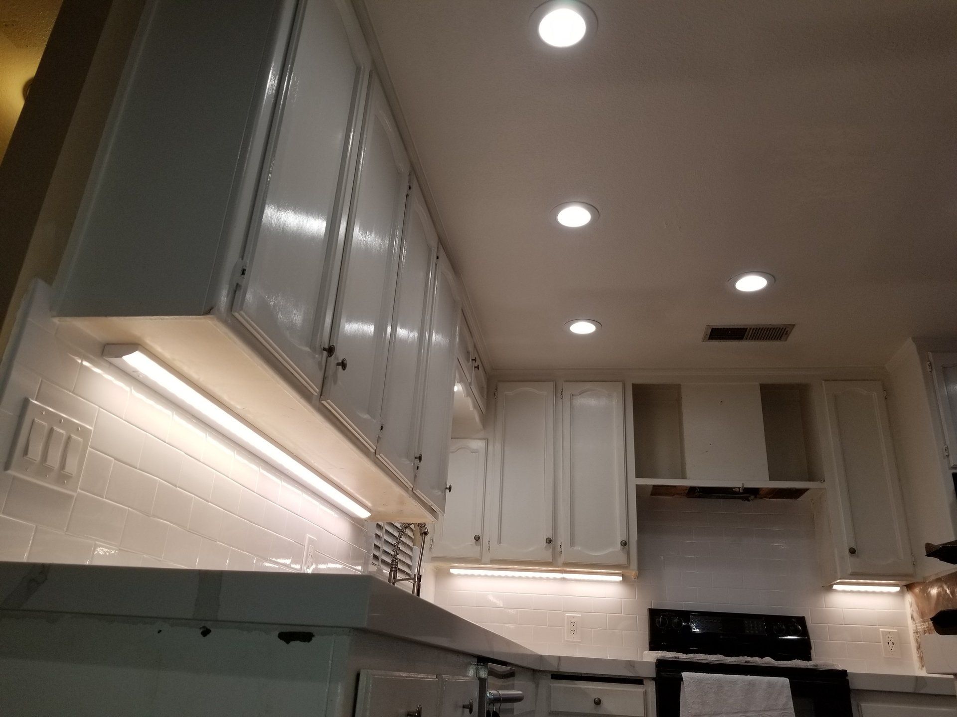 Una cucina con mobili bianchi e un piano cottura con forno nero.