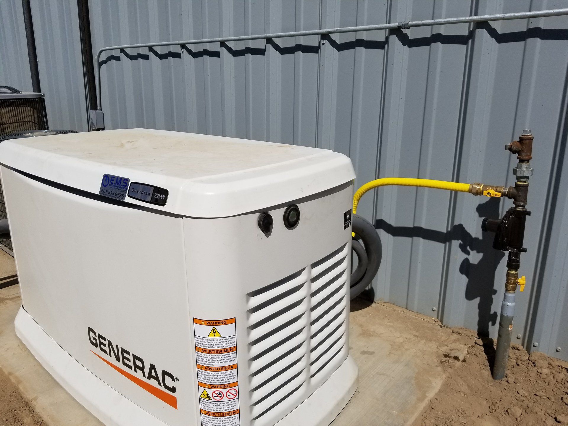 A generator is sitting on top of a concrete platform next to a gas line.