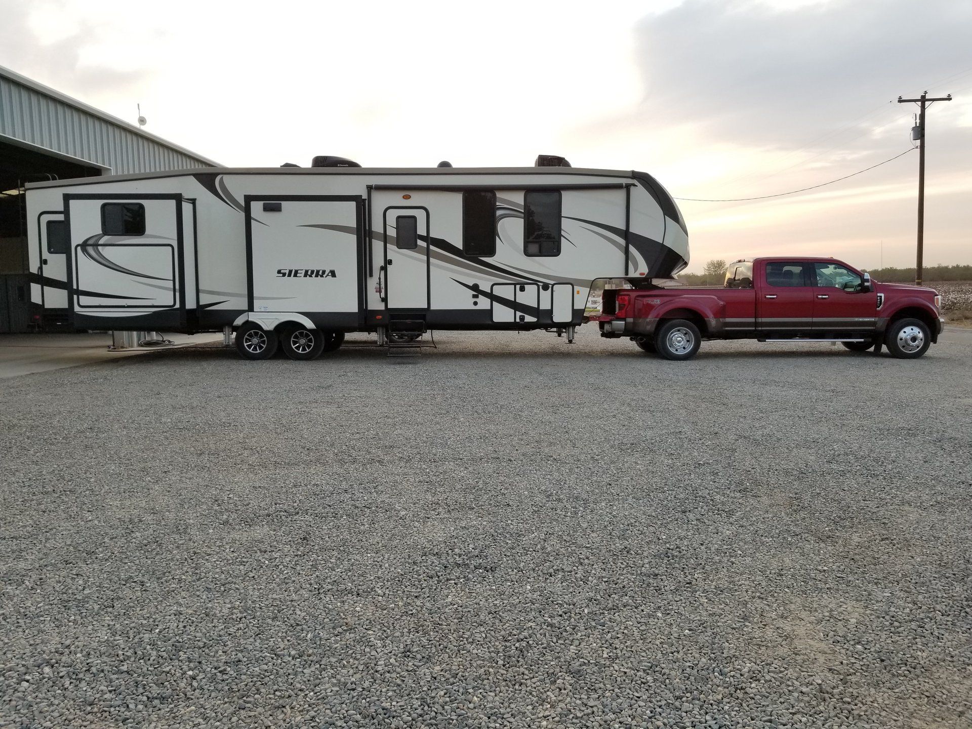 Un camion rosso traina un rimorchio in un piazzale ghiaioso.
