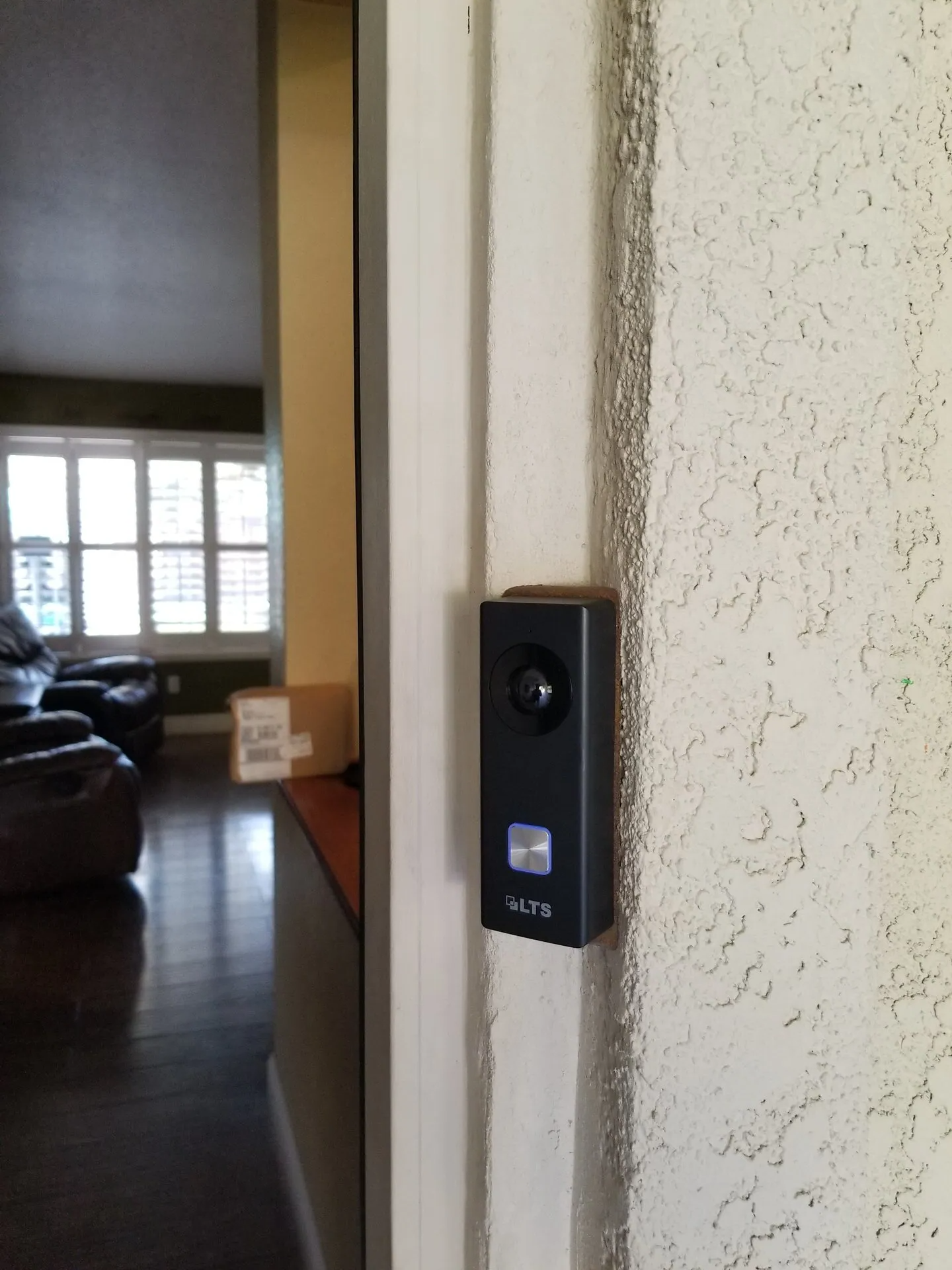 A doorbell is mounted to the side of a door in a living room.