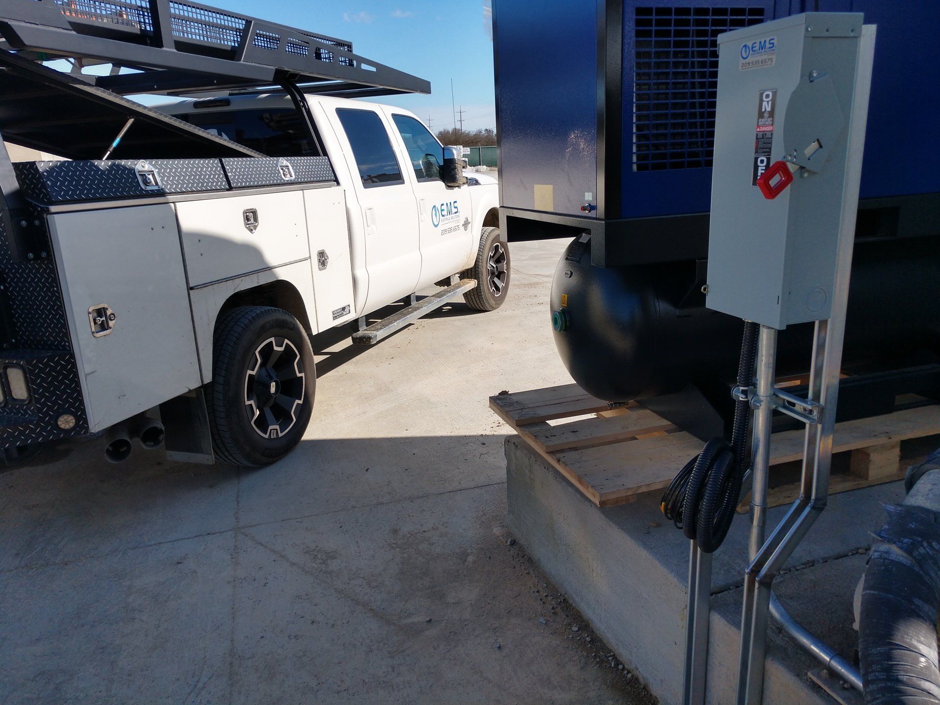 A white truck is parked next to a blue truck in a parking lot.