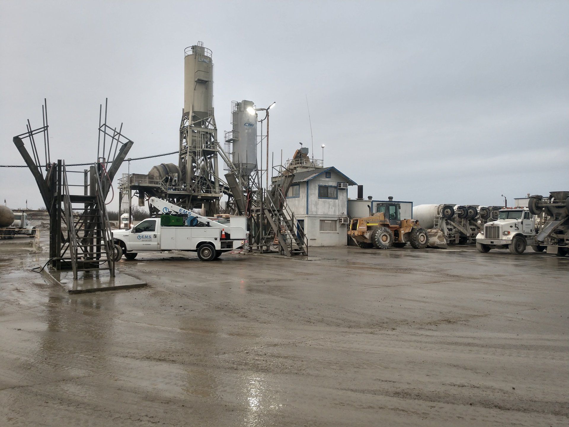 A white truck is parked in front of a concrete plant.