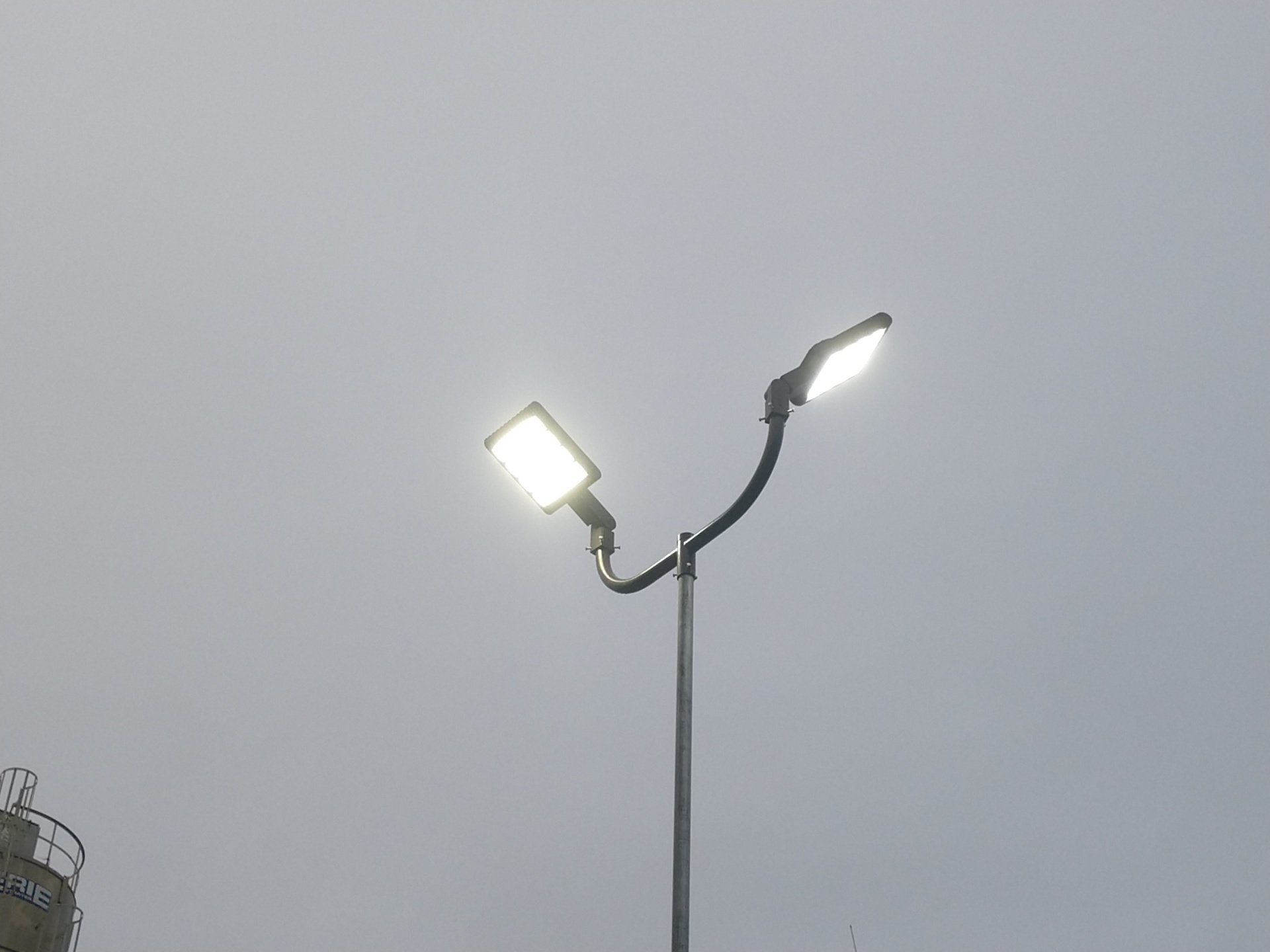 Two street lights on a pole against a cloudy sky