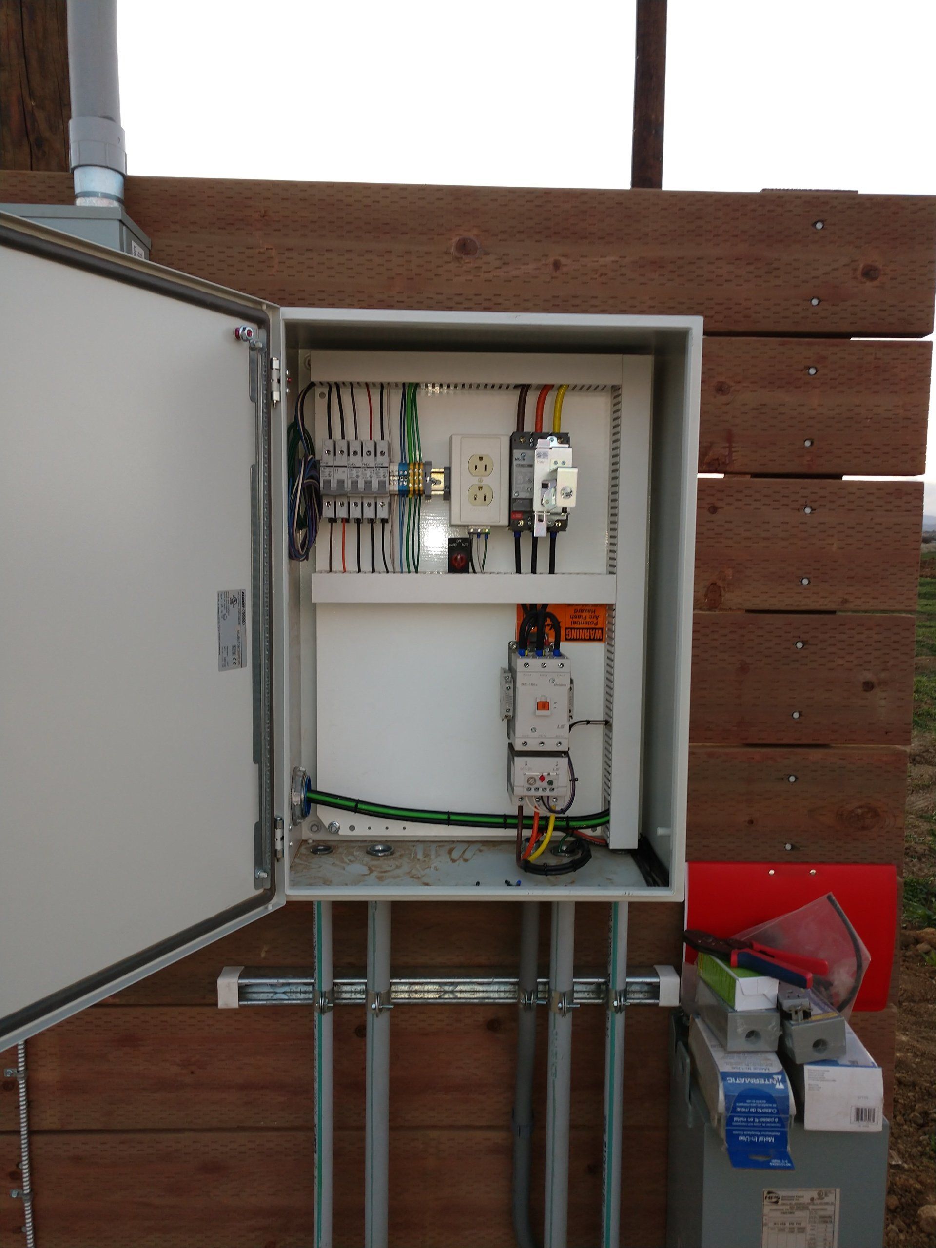 Una scatola elettrica con la porta aperta è appoggiata su una parete di legno