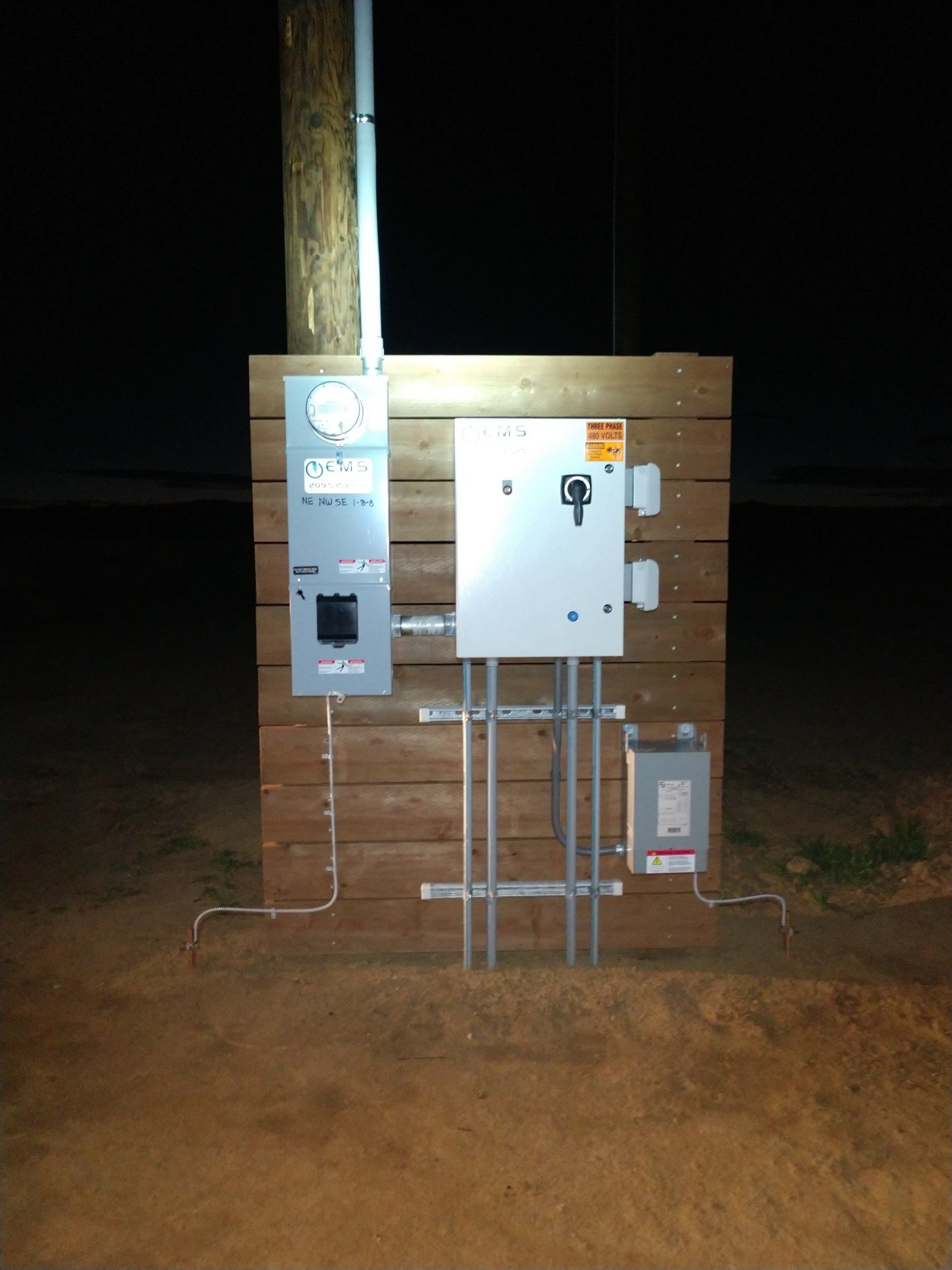 A wooden wall with electrical boxes on it at night