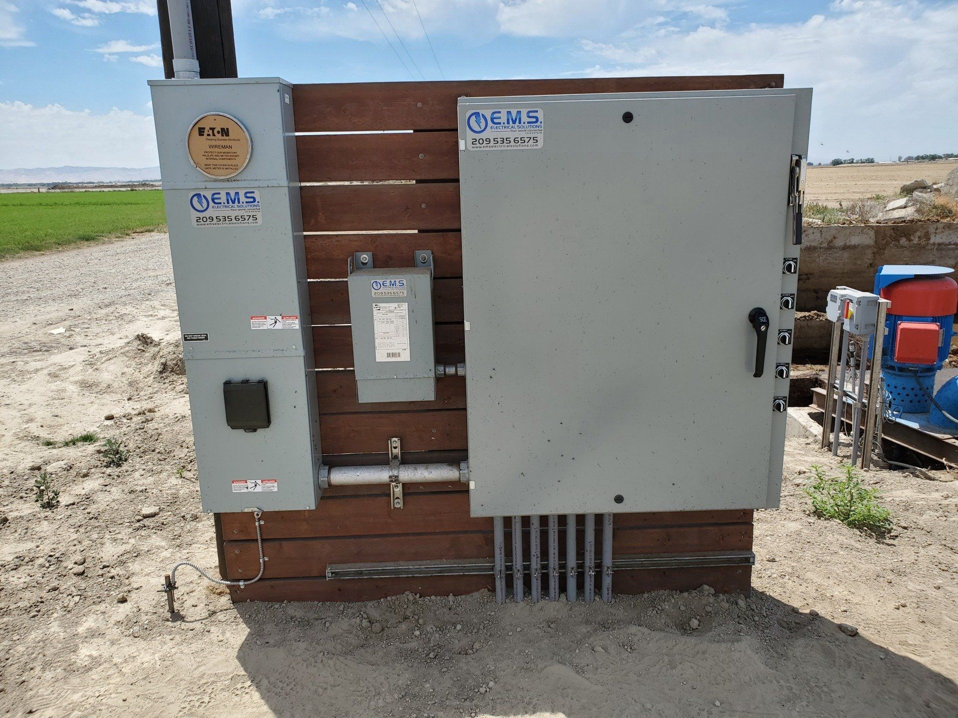 Una grande scatola elettrica si trova in mezzo a un campo sterrato.