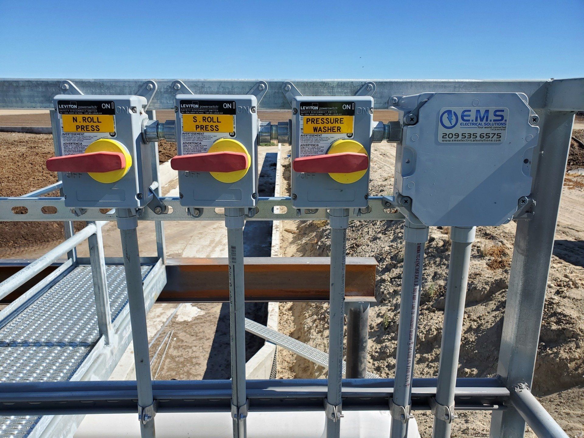 A row of electrical disconnect switches are sitting on top of a metal railing.