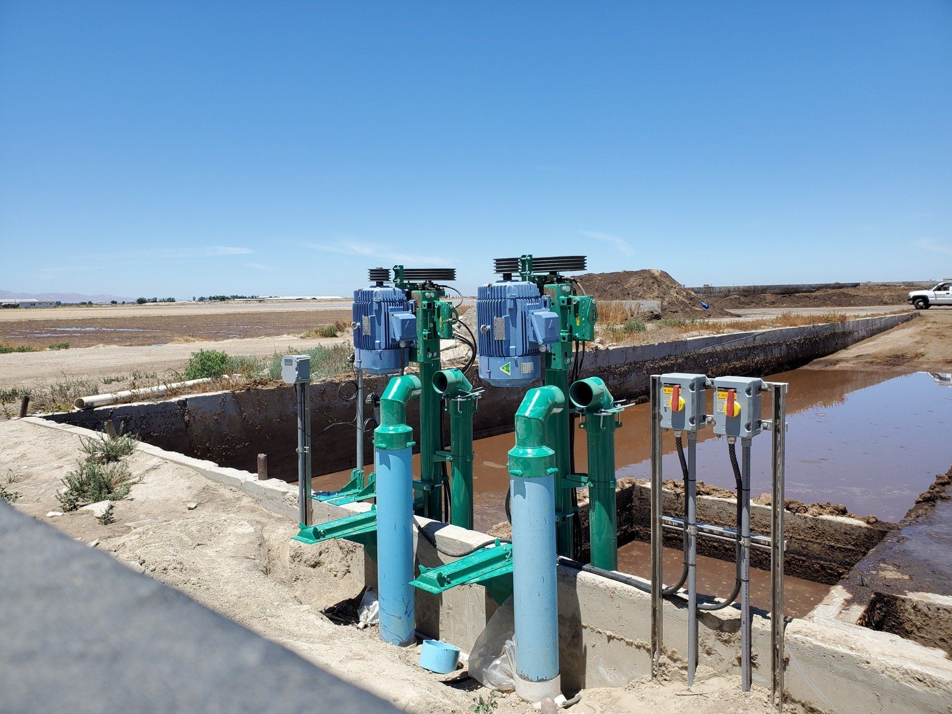 A row of green pipes are sitting next to a body of water.