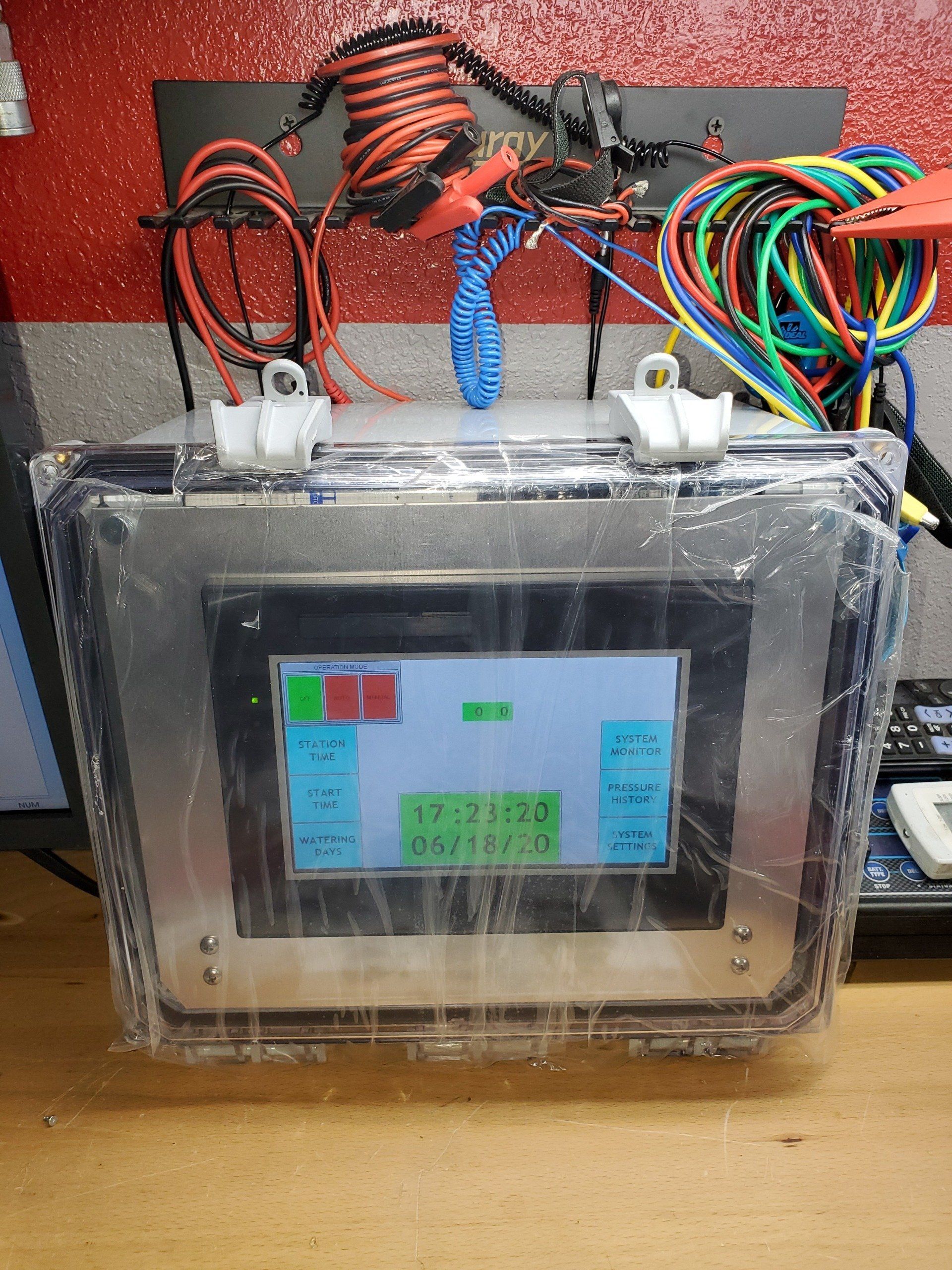 A computer monitor is sitting on a wooden table next to a bunch of wires.