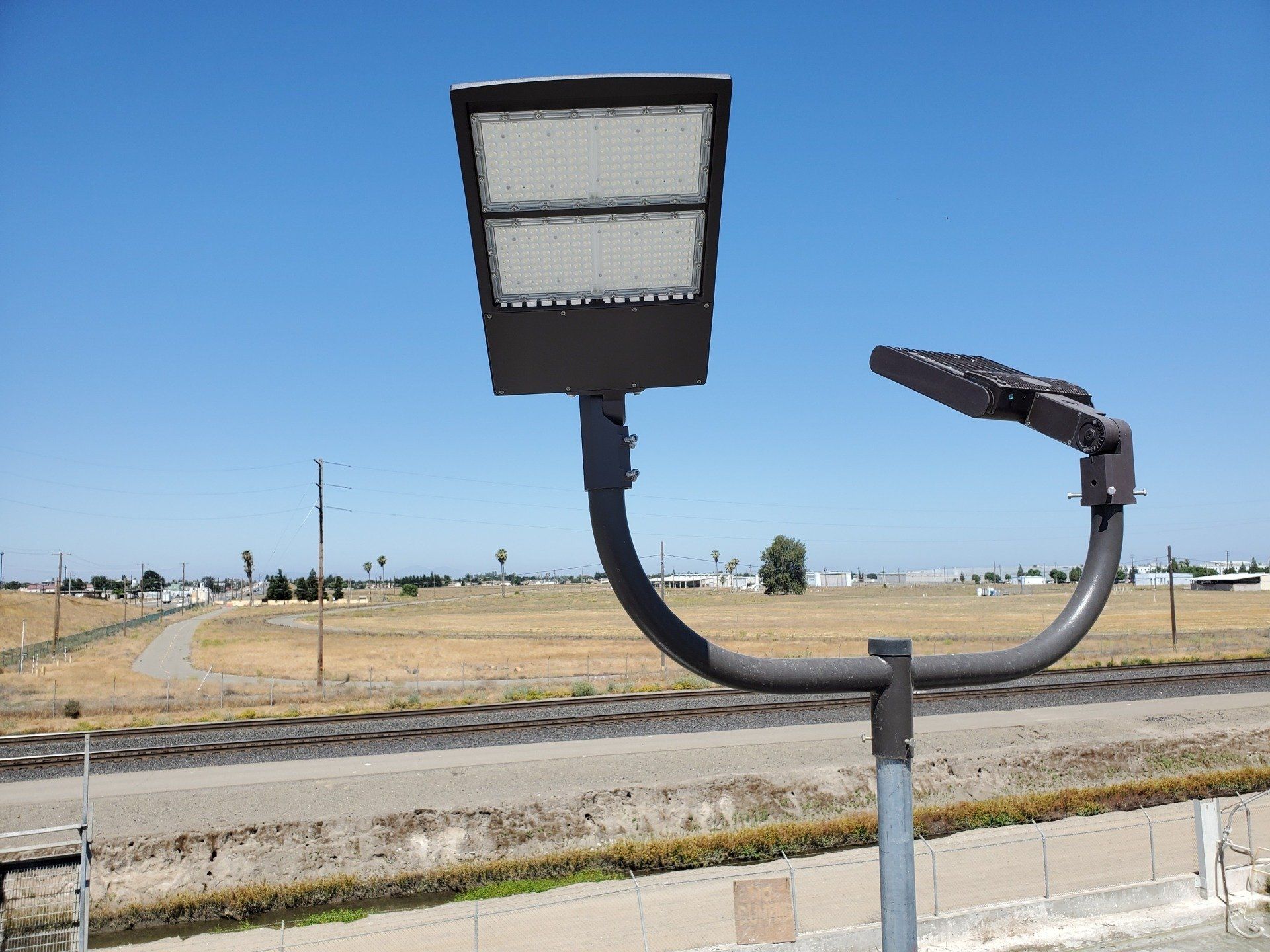 A street light is sitting on a pole in front of a train track.