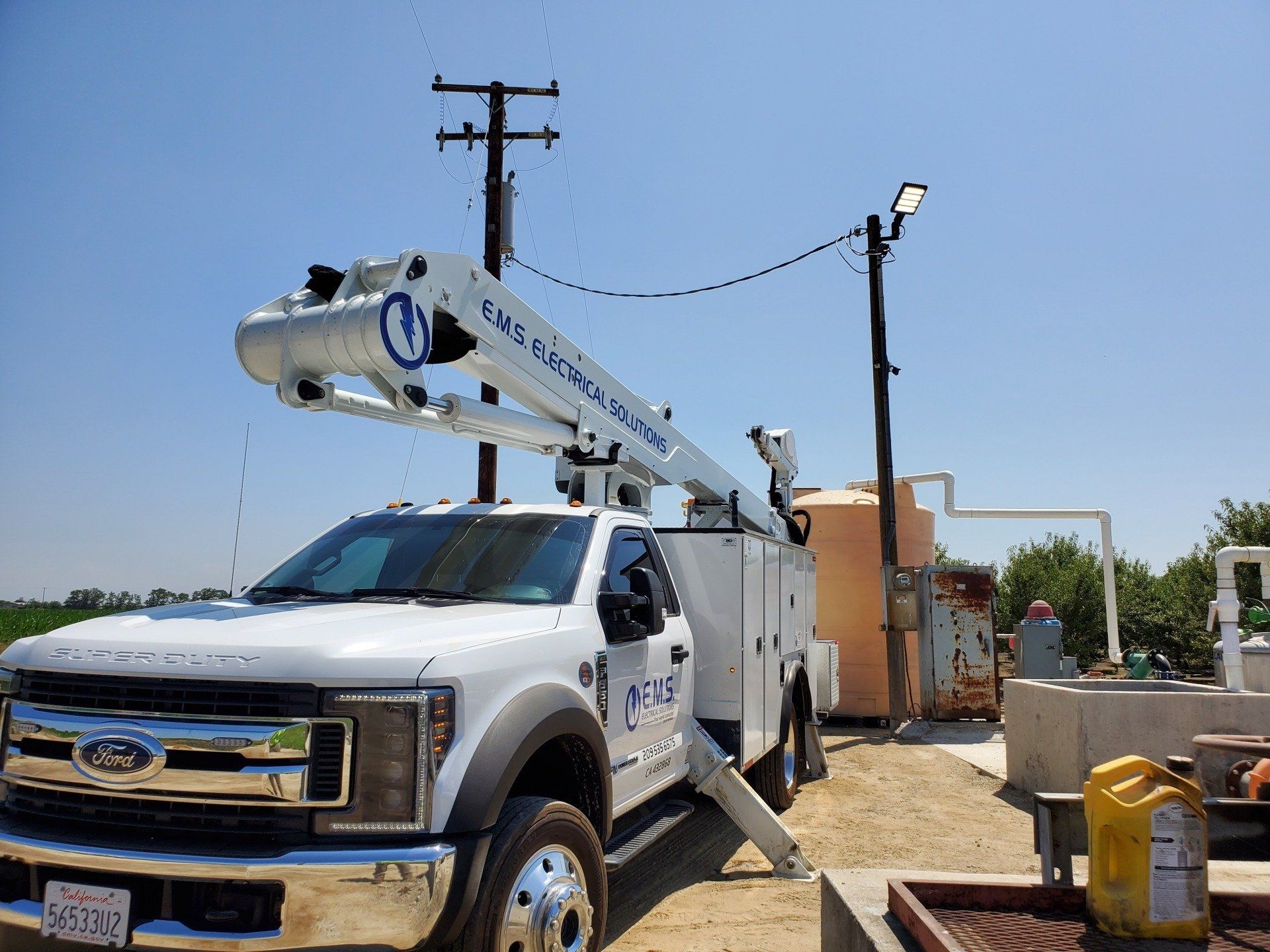 A white EMS Electrical Solutions boom truck has installed a new pole LED Flood light 