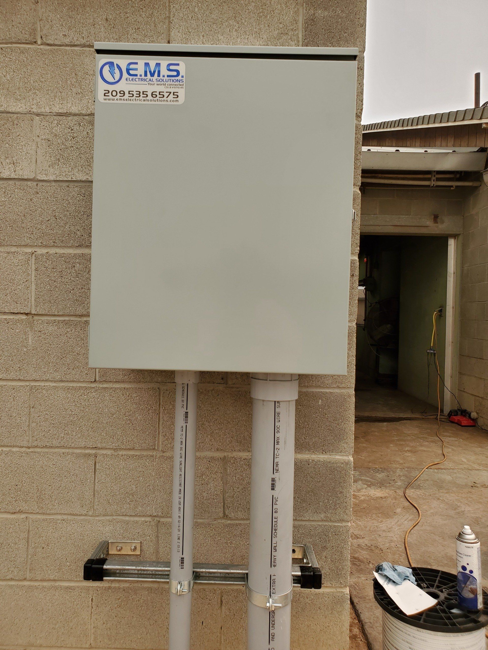 A white box is attached to a brick wall.