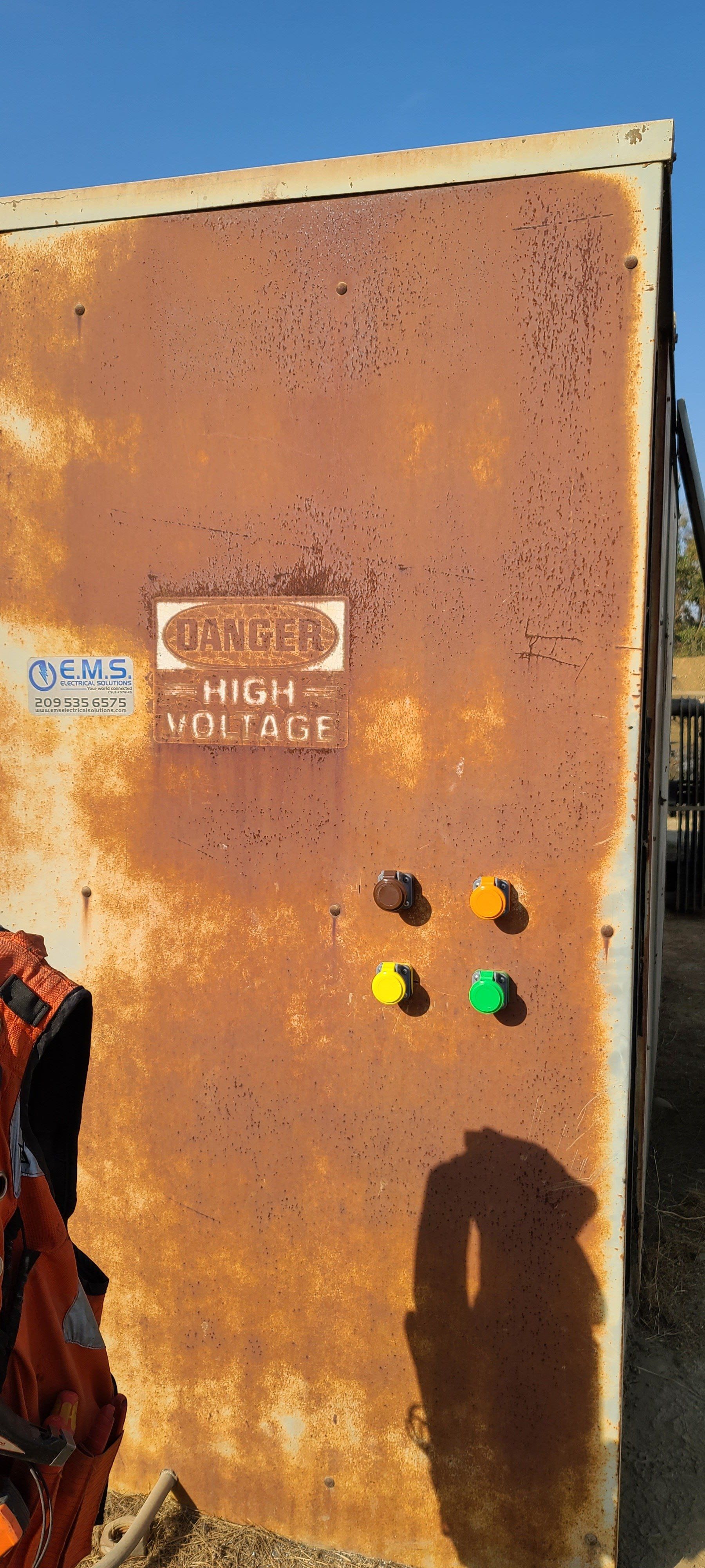 Una scatola di metallo arrugginita con un cartello che dice ``alta tensione''.