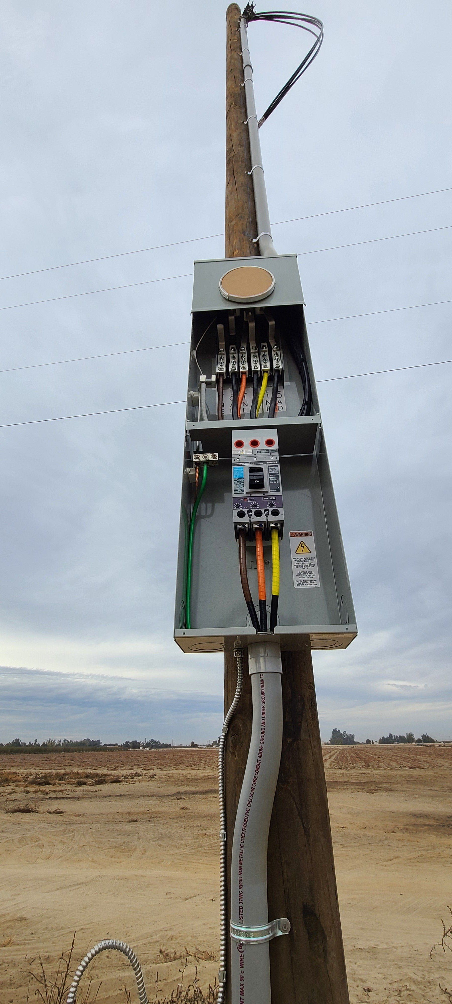 Una scatola elettrica è posizionata in cima a un palo di legno.