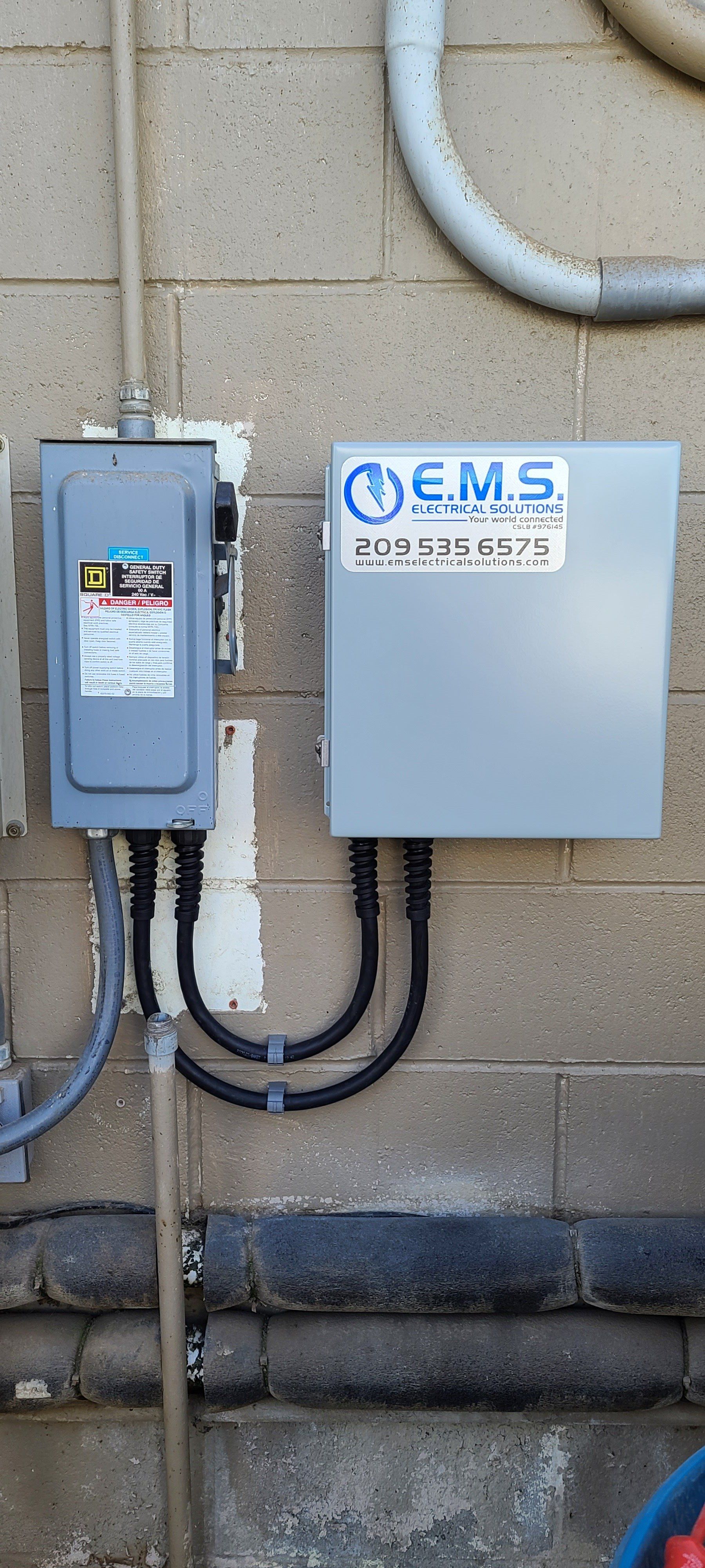 Una scatola è appesa a un muro di mattoni accanto a un tubo.