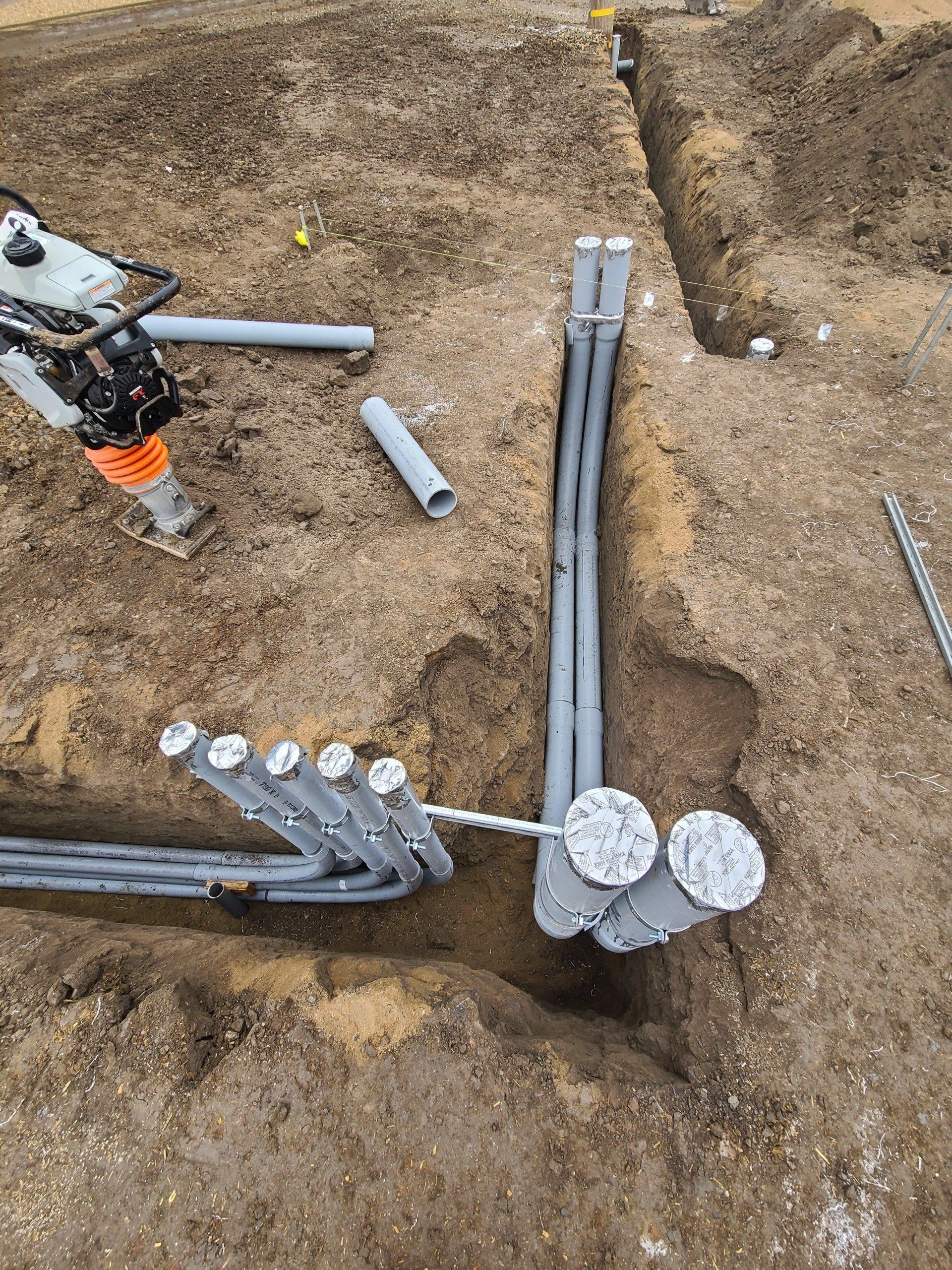 A bunch of pipes are being installed in the dirt.