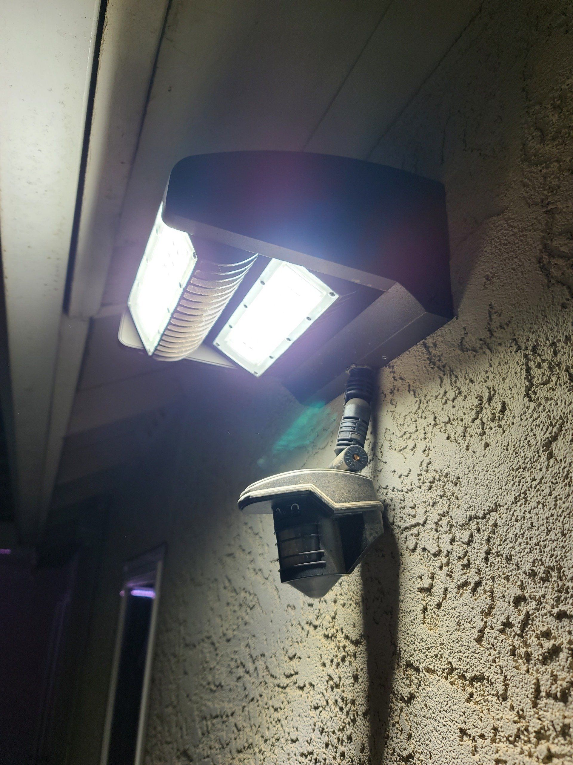 A security camera is mounted to a wall with a light on it.