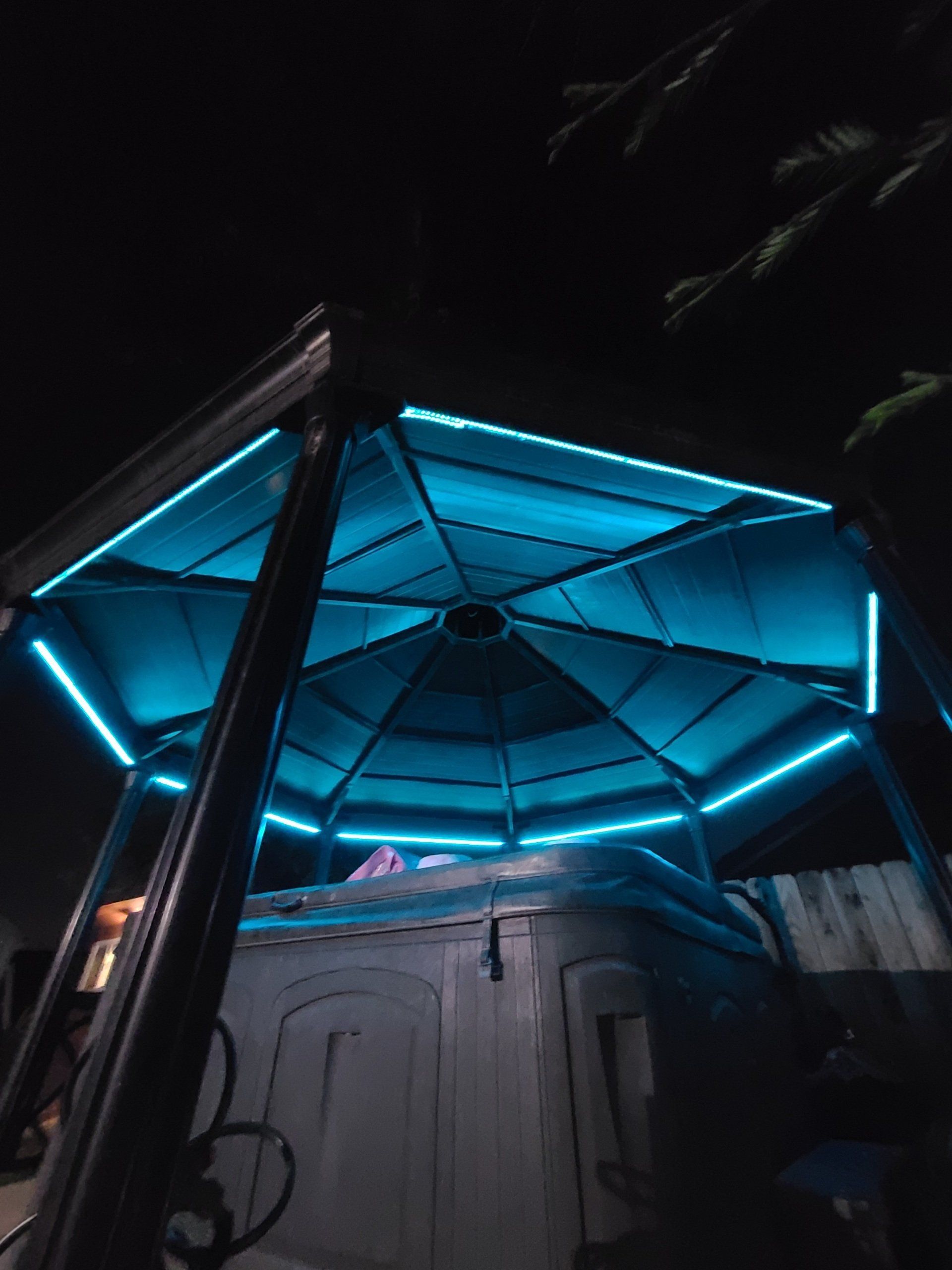 A gazebo with a hot tub inside of it at night