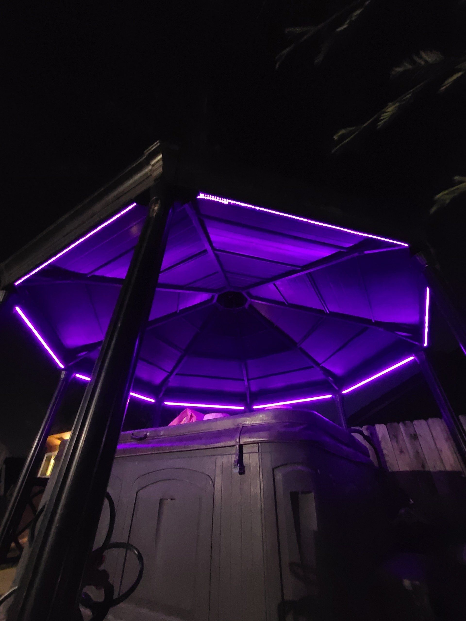 A gazebo with purple lights on it at night