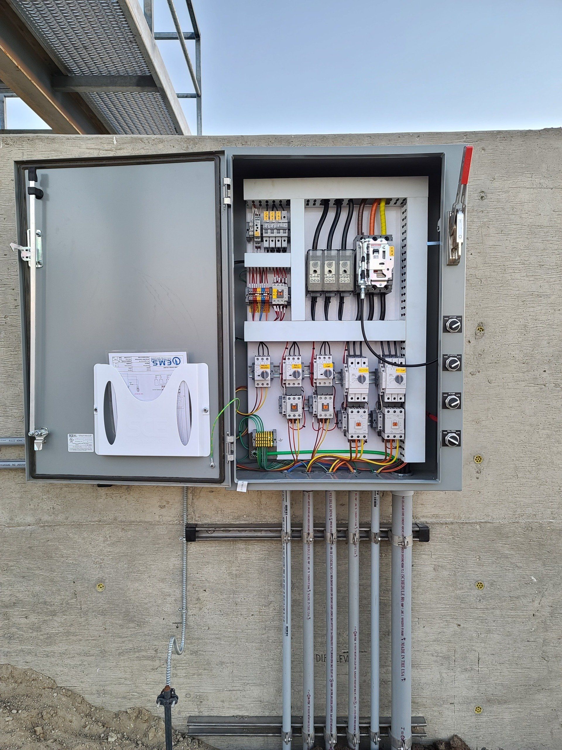 An einer Betonwand hängt ein großer Schaltkasten.