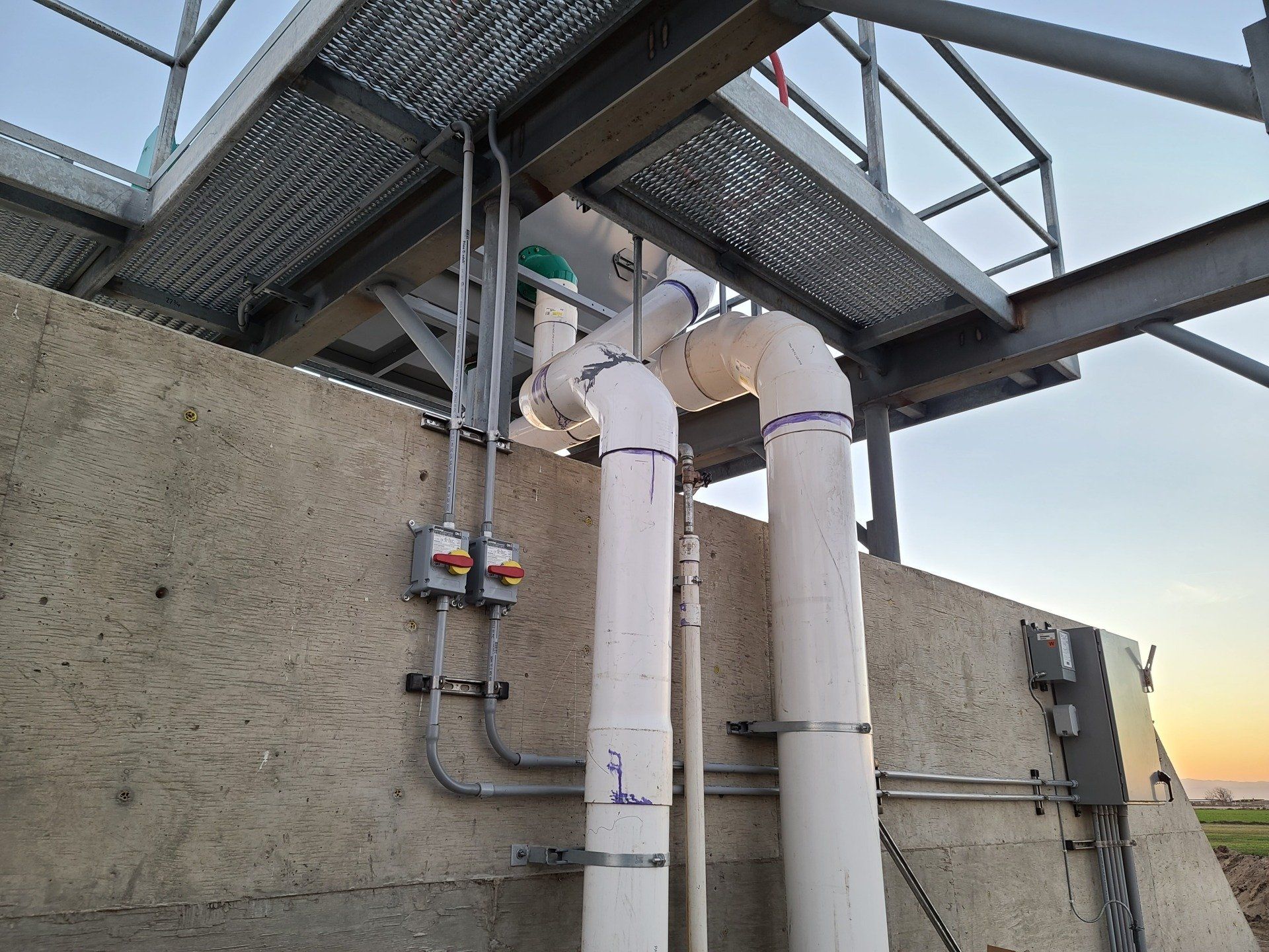 A bunch of pipes are connected to a concrete wall.