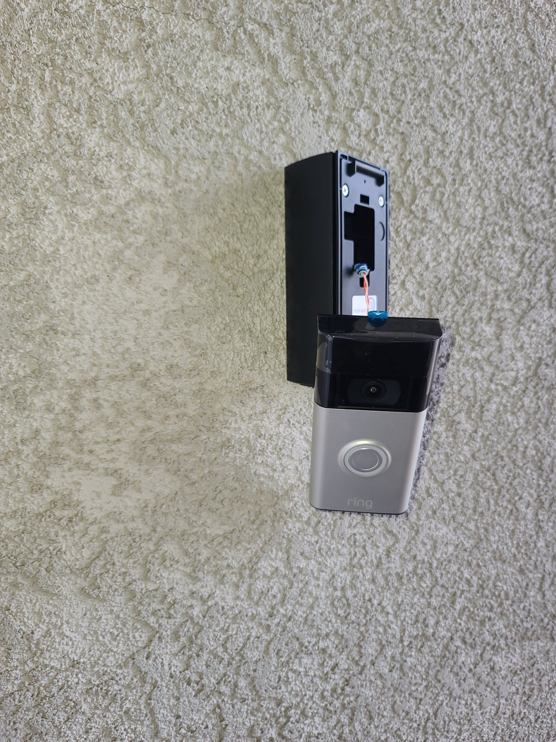 A ring doorbell is hanging on a wall.