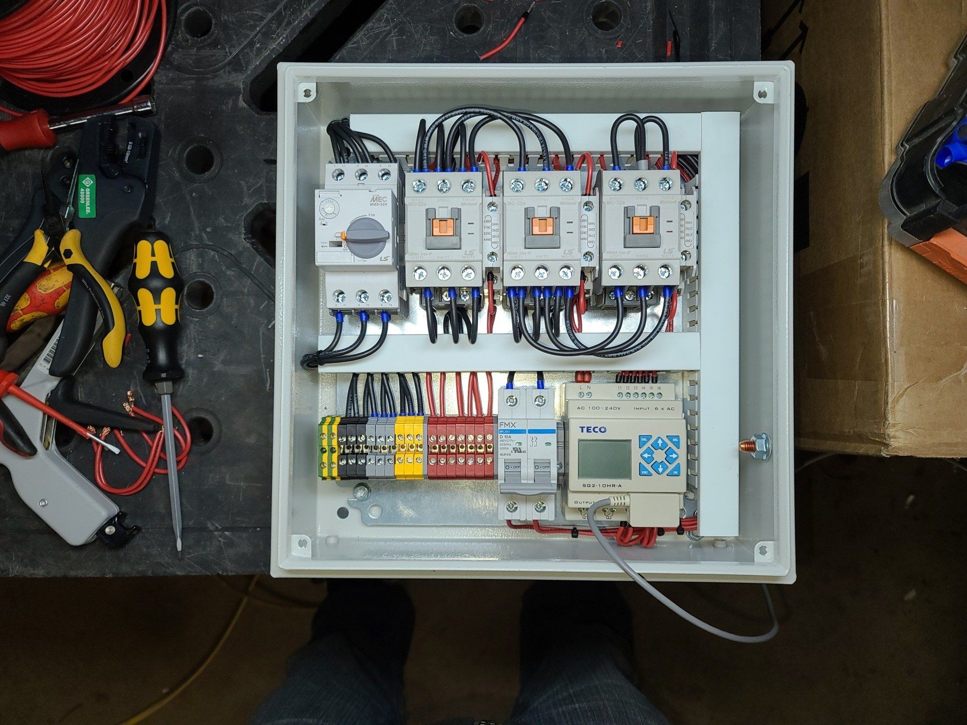 Una persona sta lavorando su una scatola elettrica con molti fili