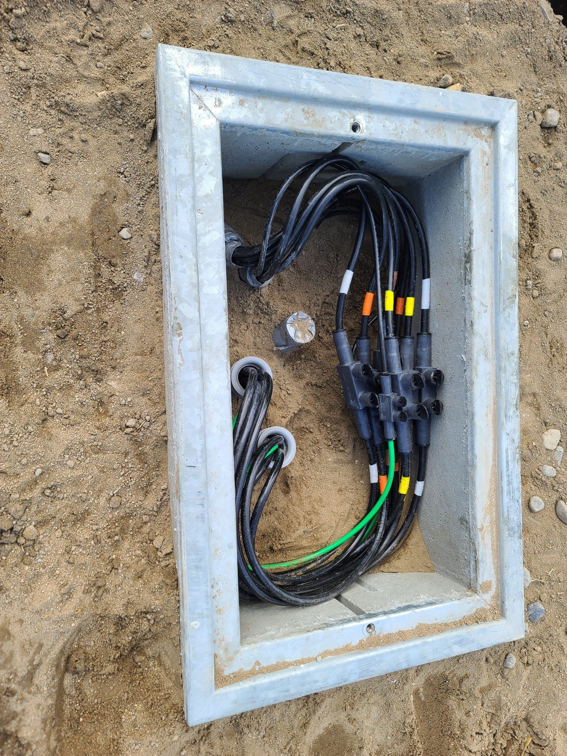 Una scatola piena di cavi elettrici è abbandonata nella terra.