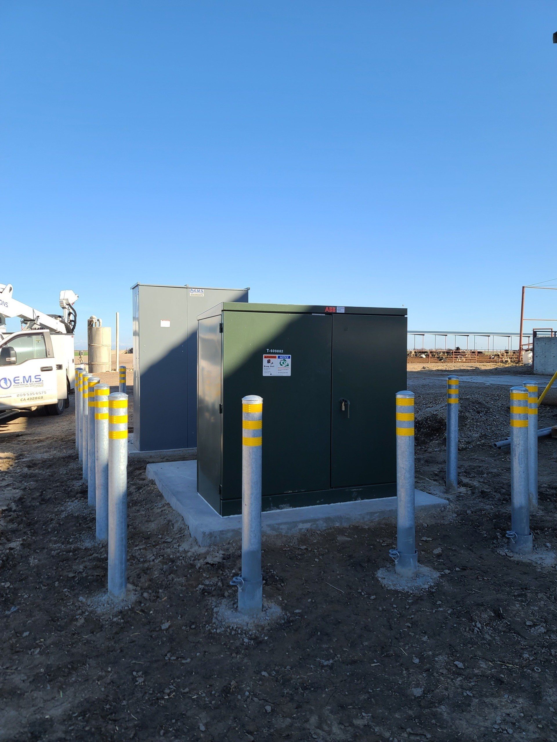 Una scatola verde è posta in mezzo a un campo sterrato circondato da pali gialli.