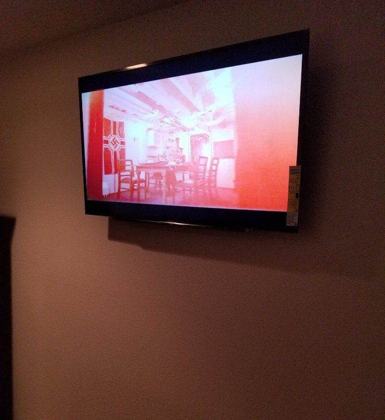 A flat screen tv is hanging on a white wall