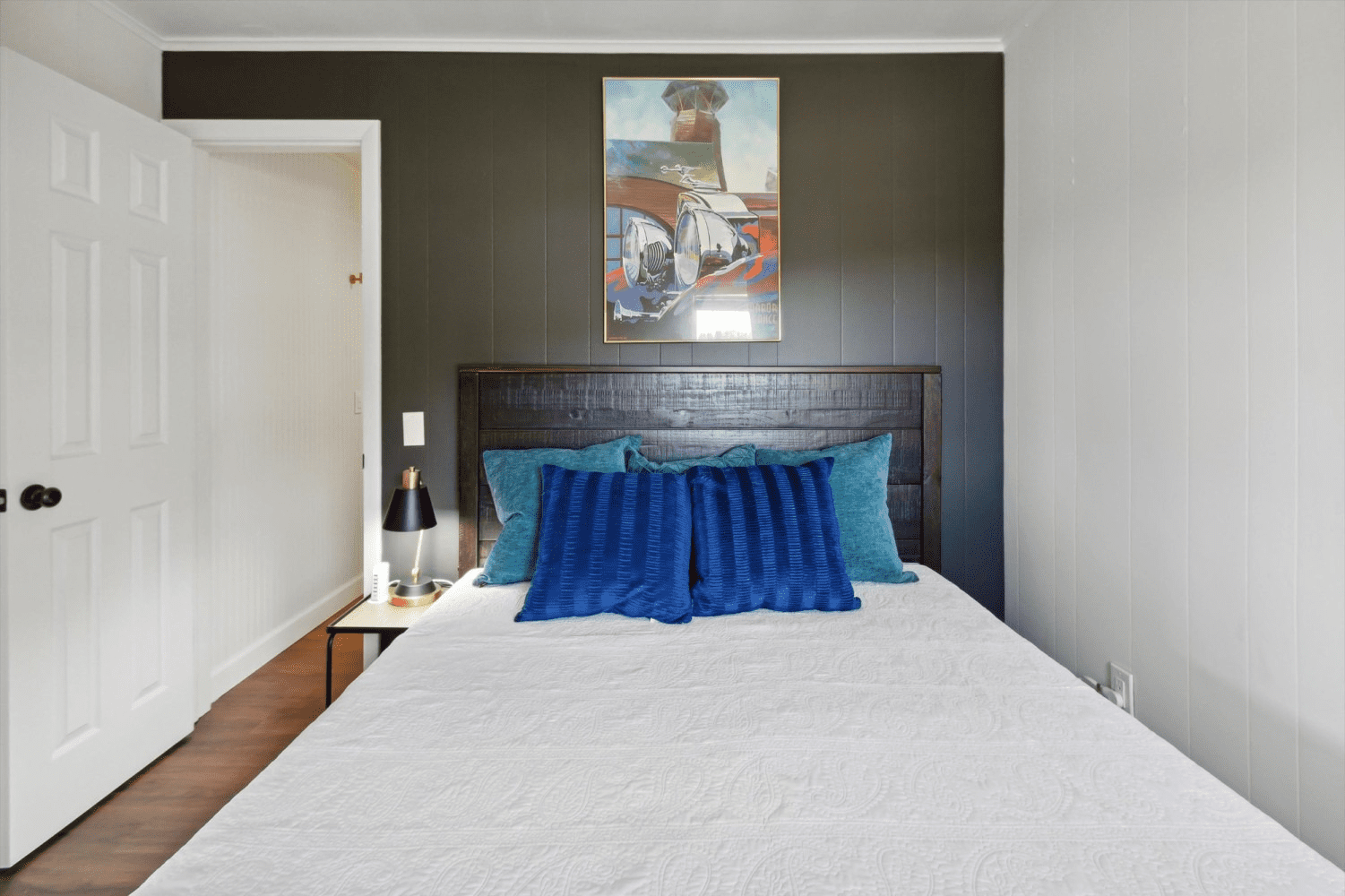 A bedroom with a bed and a painting on the wall above it.