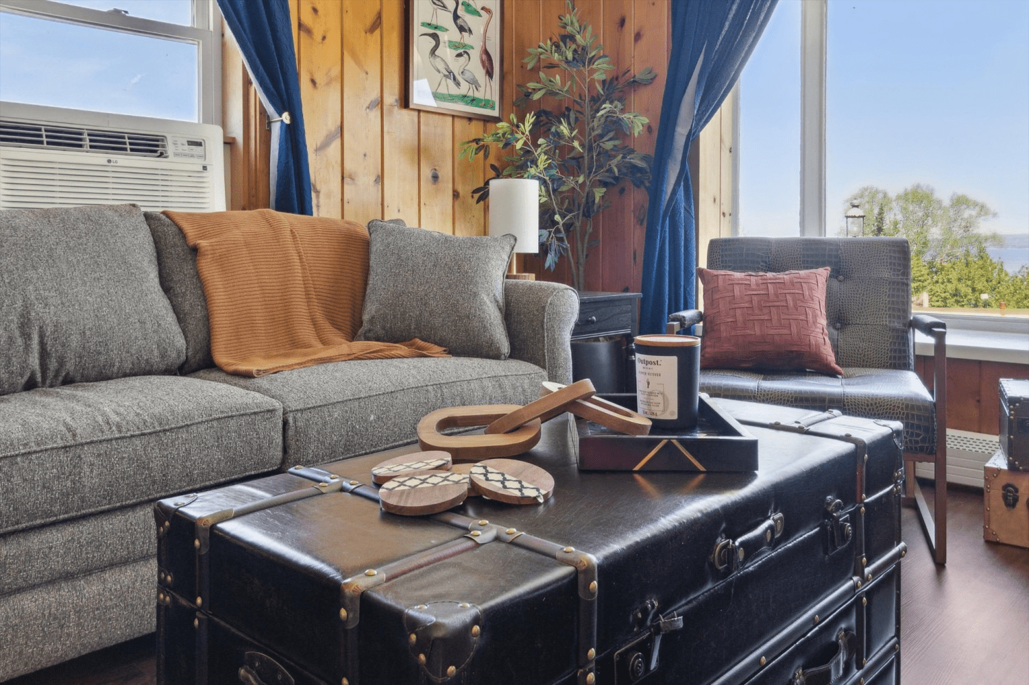 A living room with a couch , chair , coffee table and window.