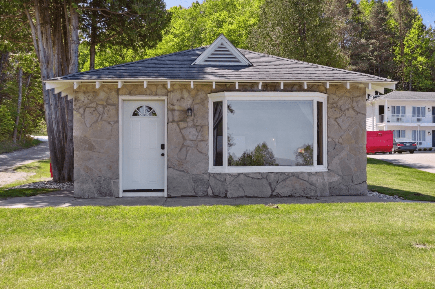 A small stone house with a white door and a large window.