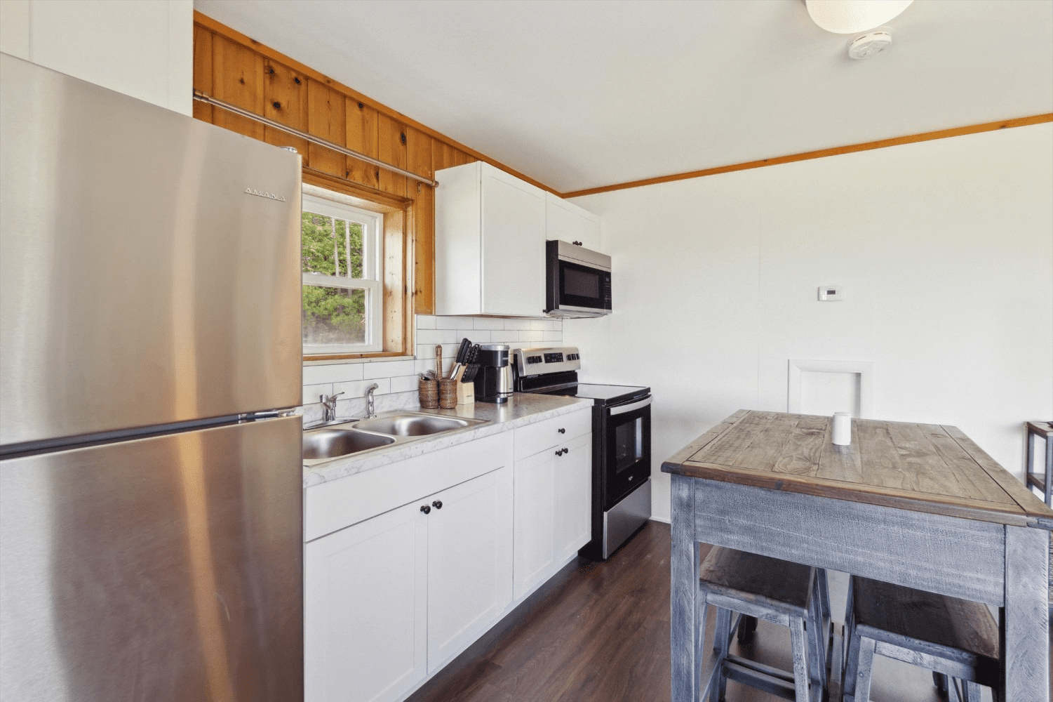 A kitchen with a stainless steel refrigerator , stove , sink and table.