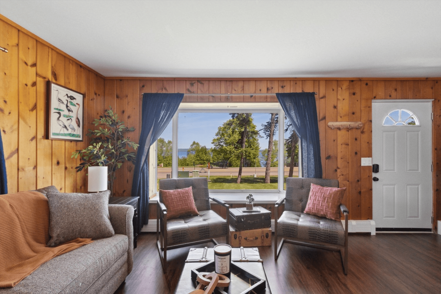 A living room with wood paneling and a large window.