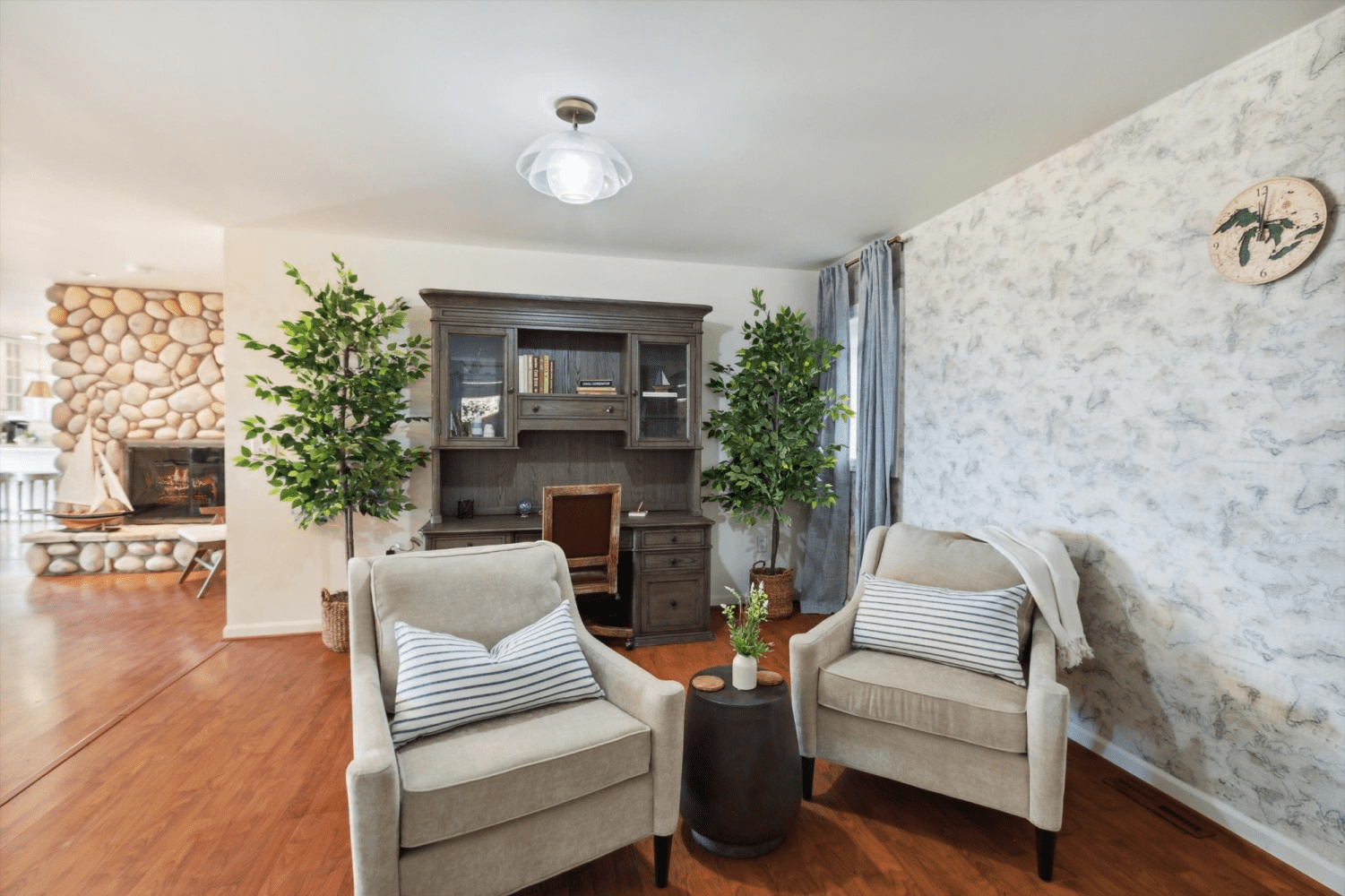 A living room with two chairs , a desk and a fireplace.