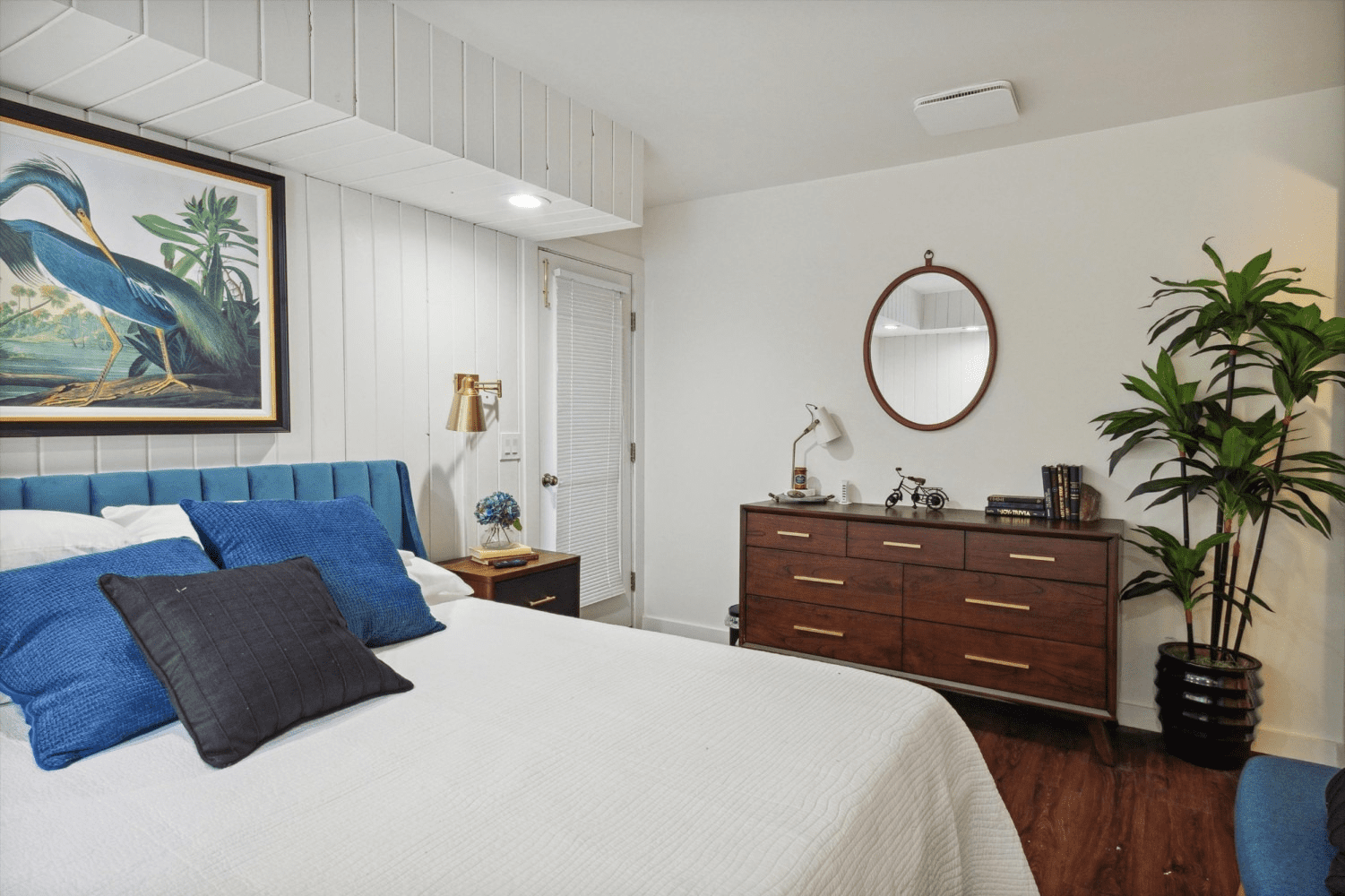 A bedroom with a bed , dresser , and mirror.